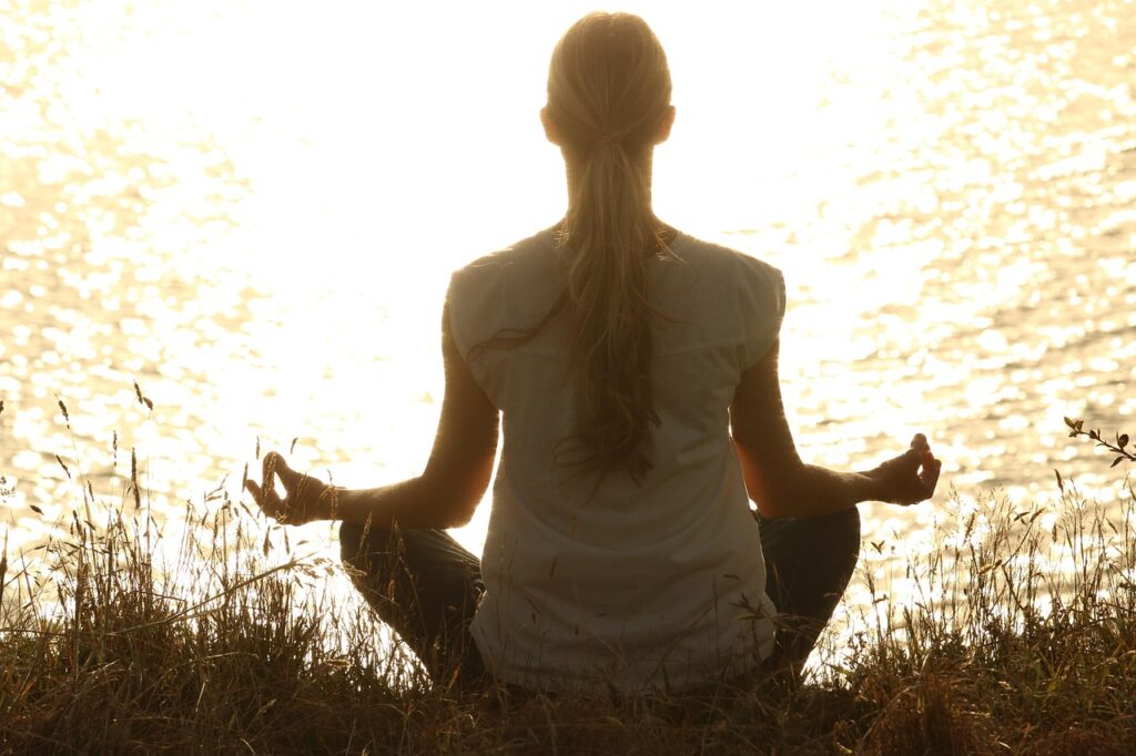 woman meditating by the lake