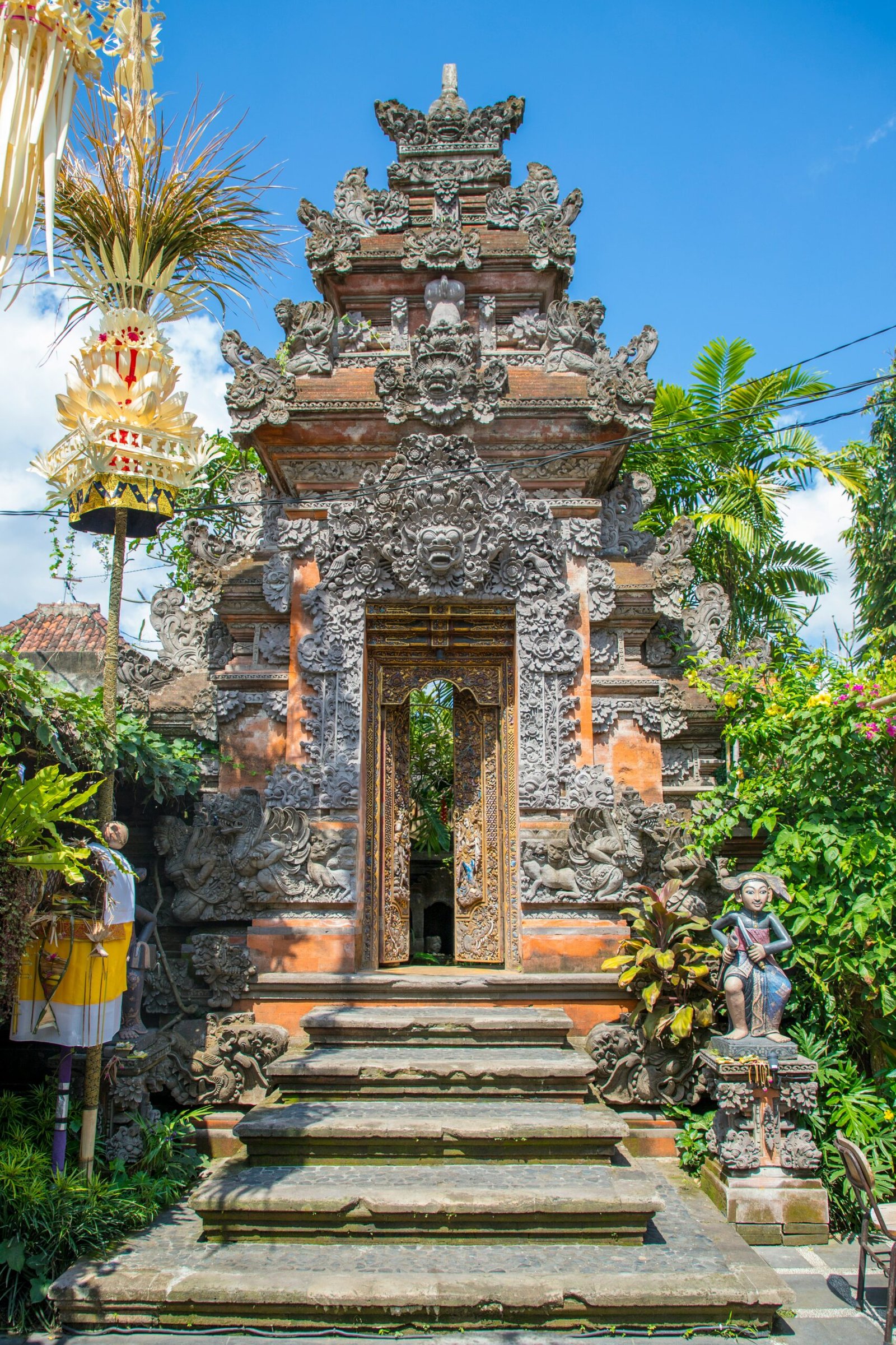 An intricate stone-carved Balinese temple gateway (Candi Bentar) adorned with traditional sculptures and gold-leafed doors, representing the spiritual heart of a Bali yoga retreat.