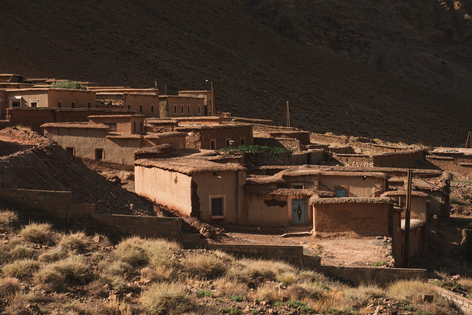 A cluster of traditional clay-built houses in a Berber village within the High Atlas Mountains of Morocco, illustrating an authentic setting for an October yoga and cultural retreat.