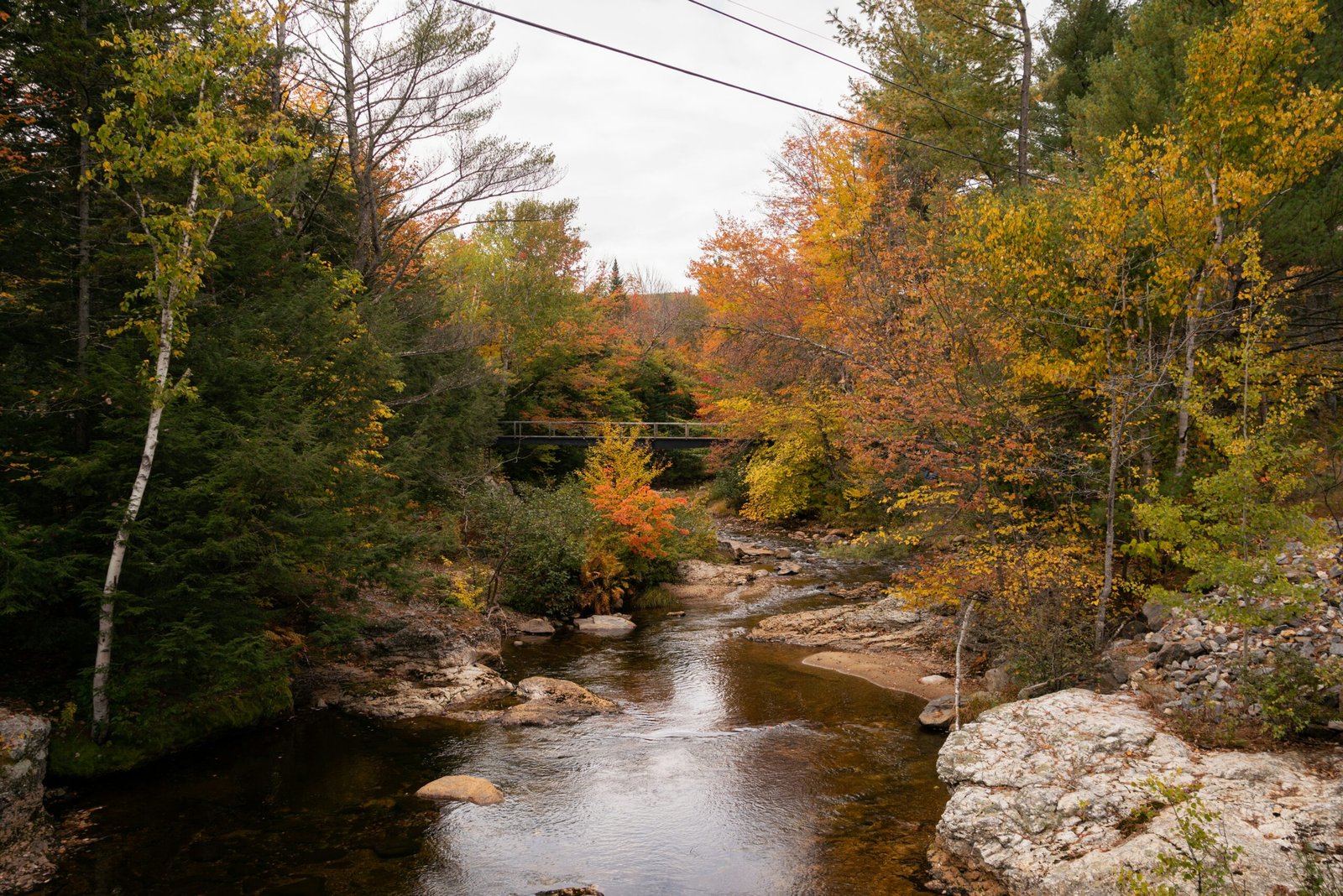 Vermont river bordered by bright fall foliage and rocky banks in a quiet woodland setting.