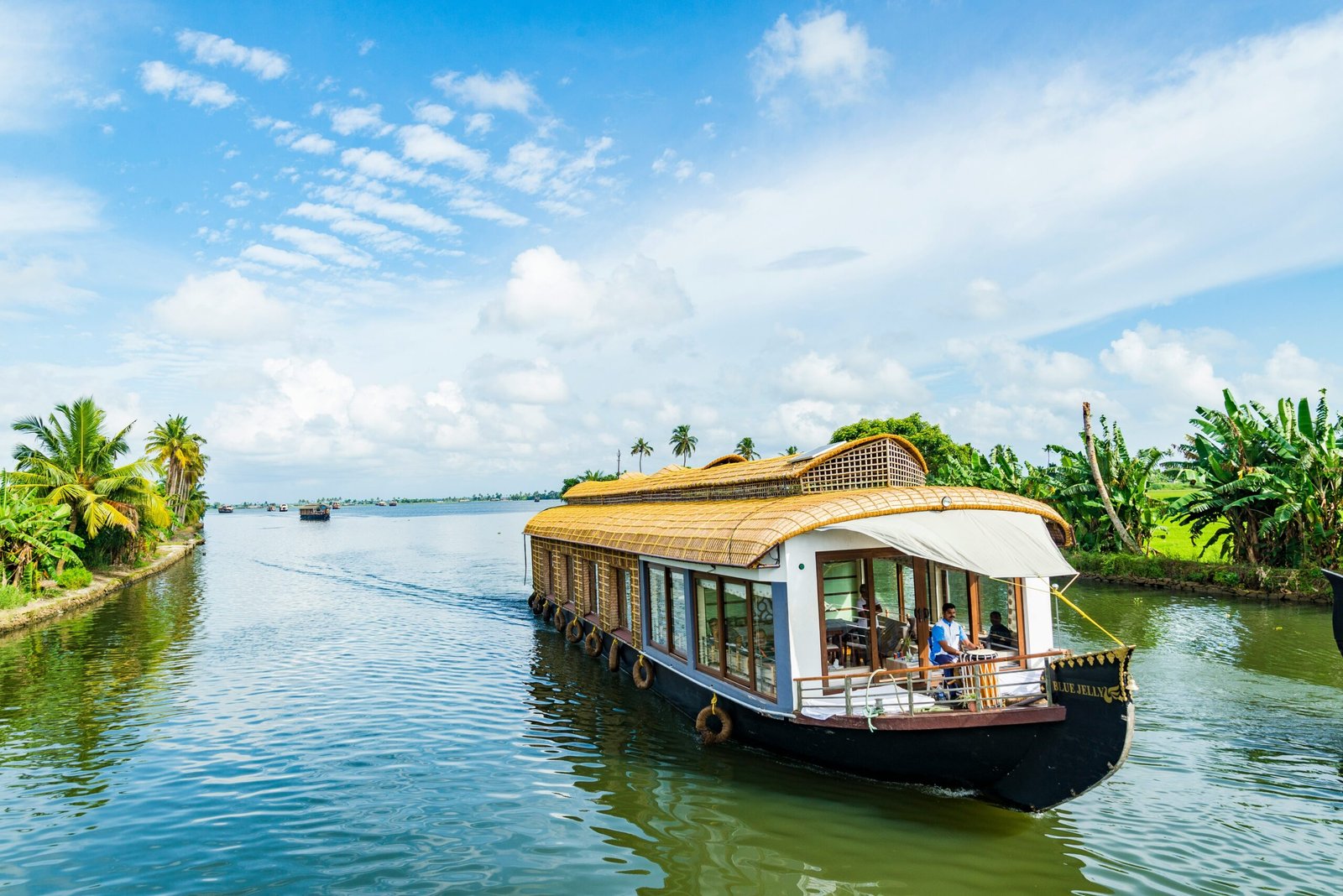 Houseboat gliding through the Alleppey backwaters, evoking the slow and restorative rhythm of a monsoon retreat in Kerala.
