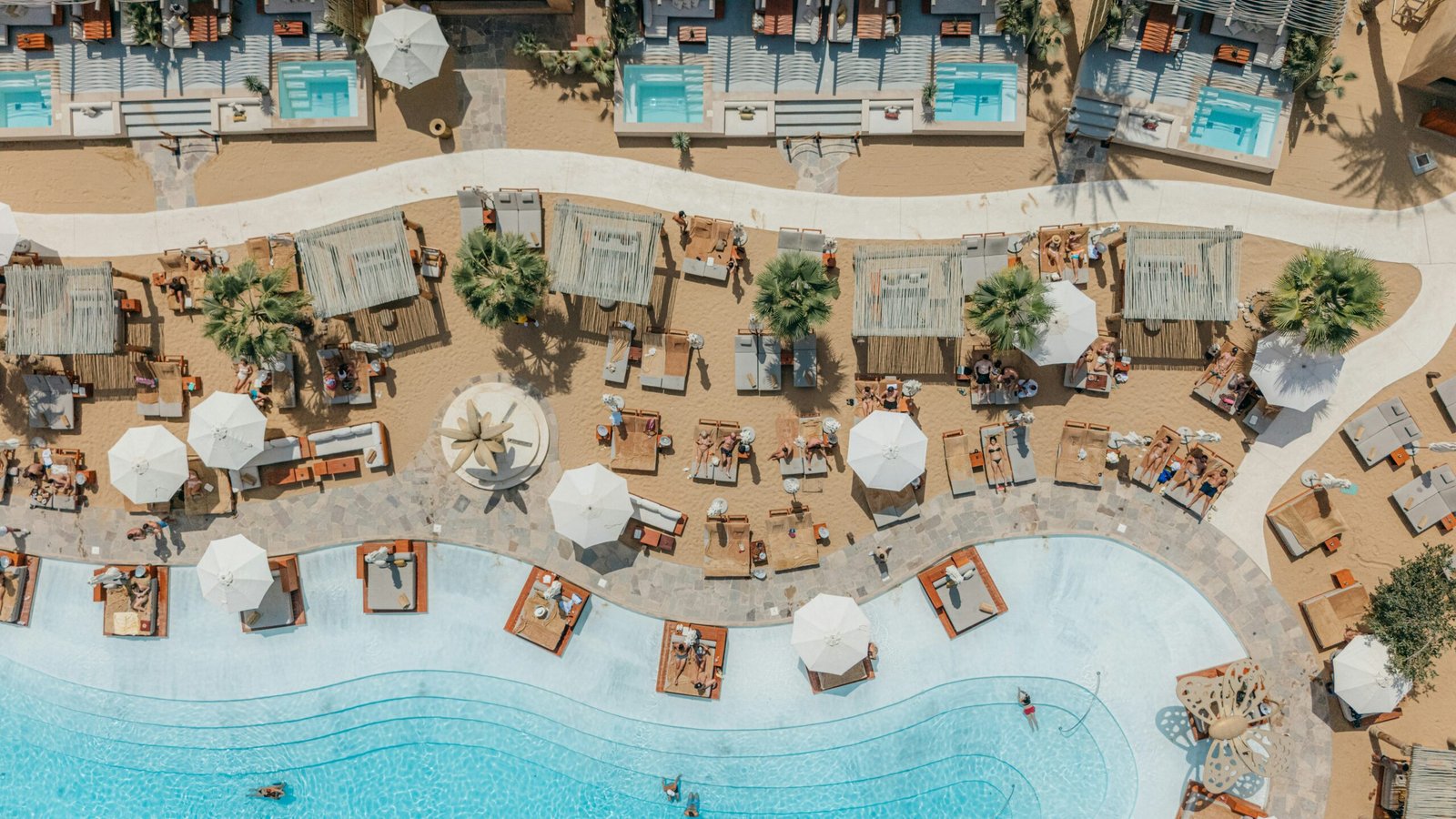 Luxury beach resort with pools and loungers suited to a high-summer wellness getaway.