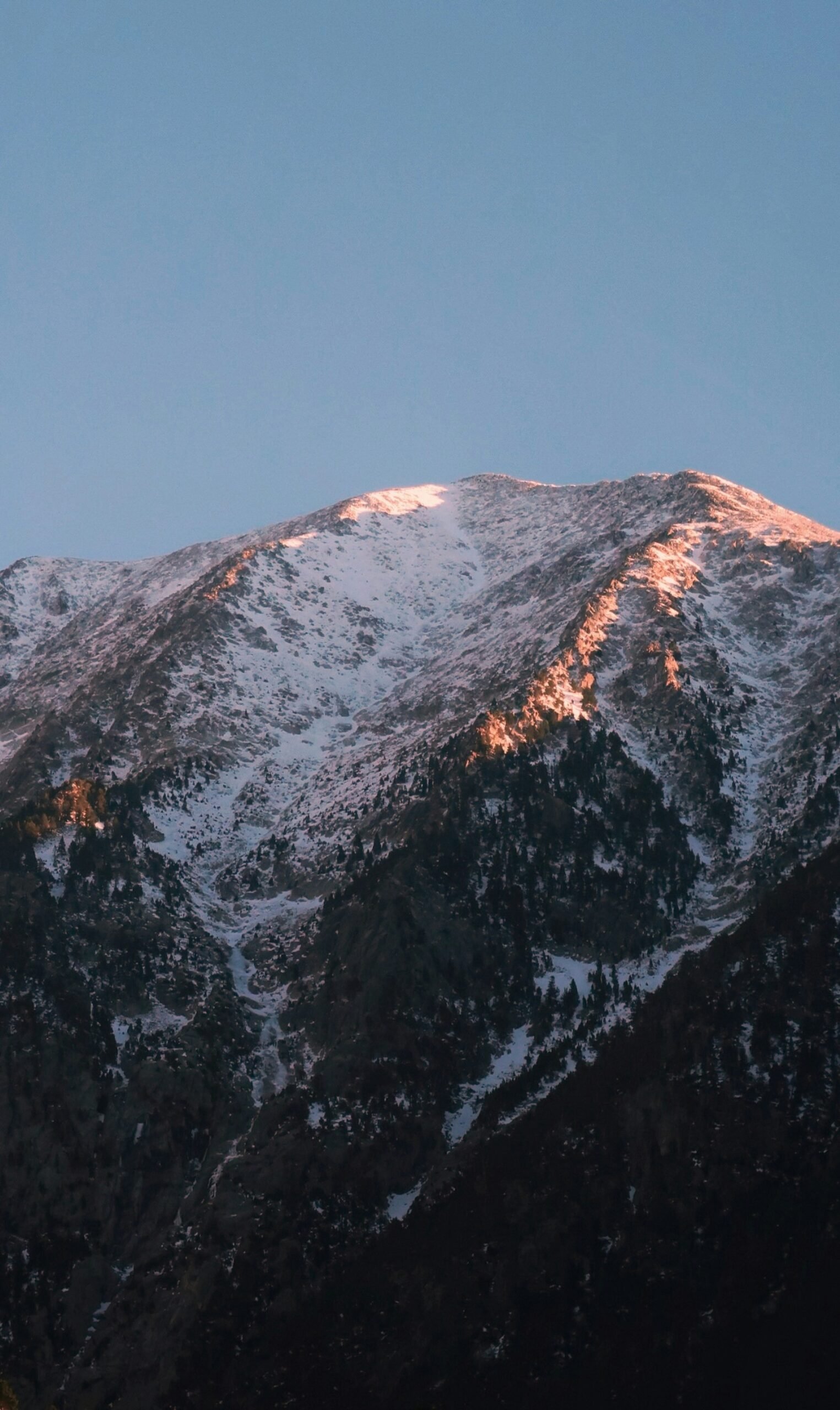 Snow-covered mountain peak in the Sierra Nevada, Spain, illuminated by golden-hour sunlight.