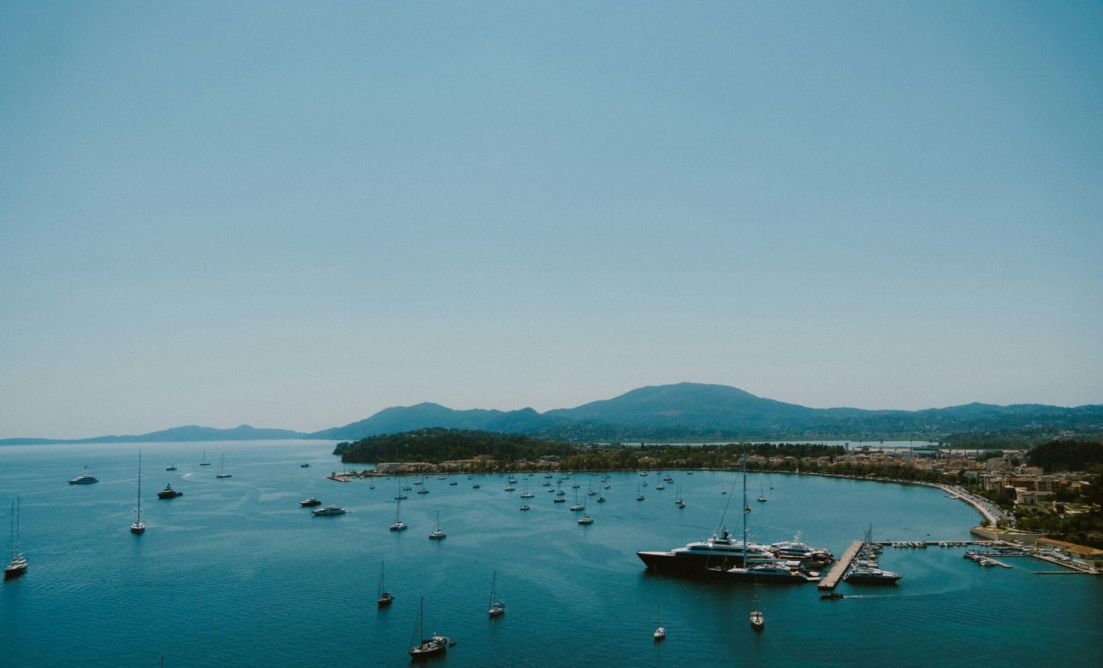 Spring harbor view in Corfu with quiet water and anchored boats for an easygoing island retreat setting.