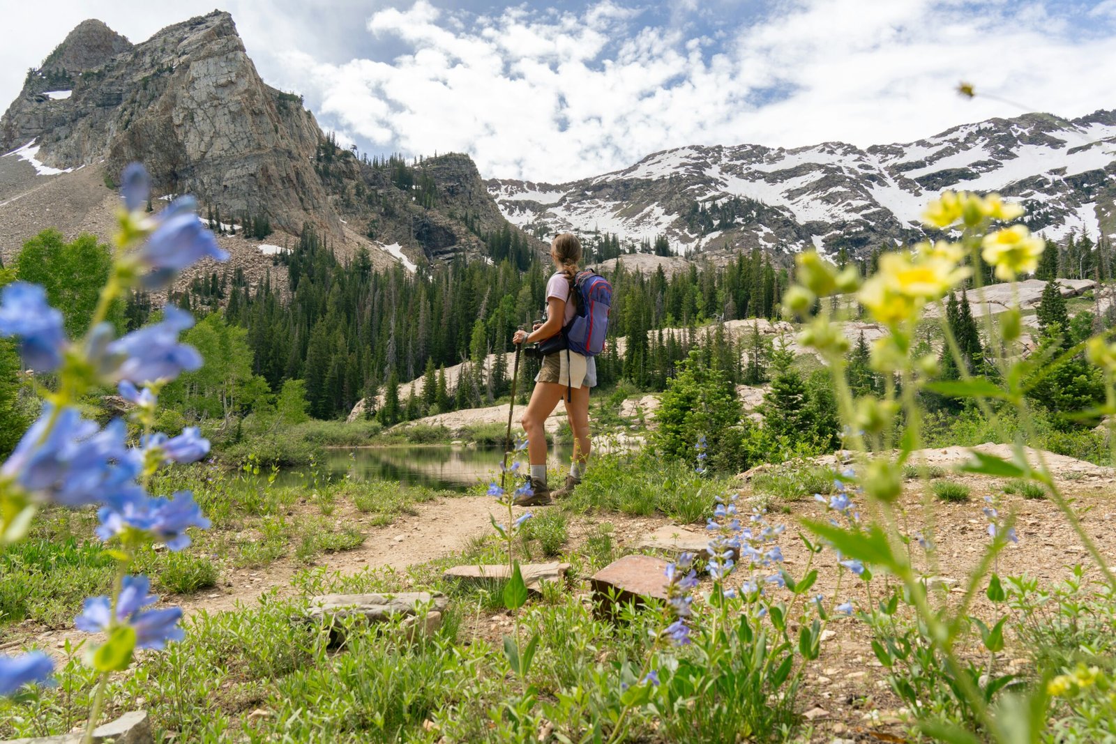 Woman hiking along a mountain trail lined with wildflowers near Lake Blanche in Utah.
