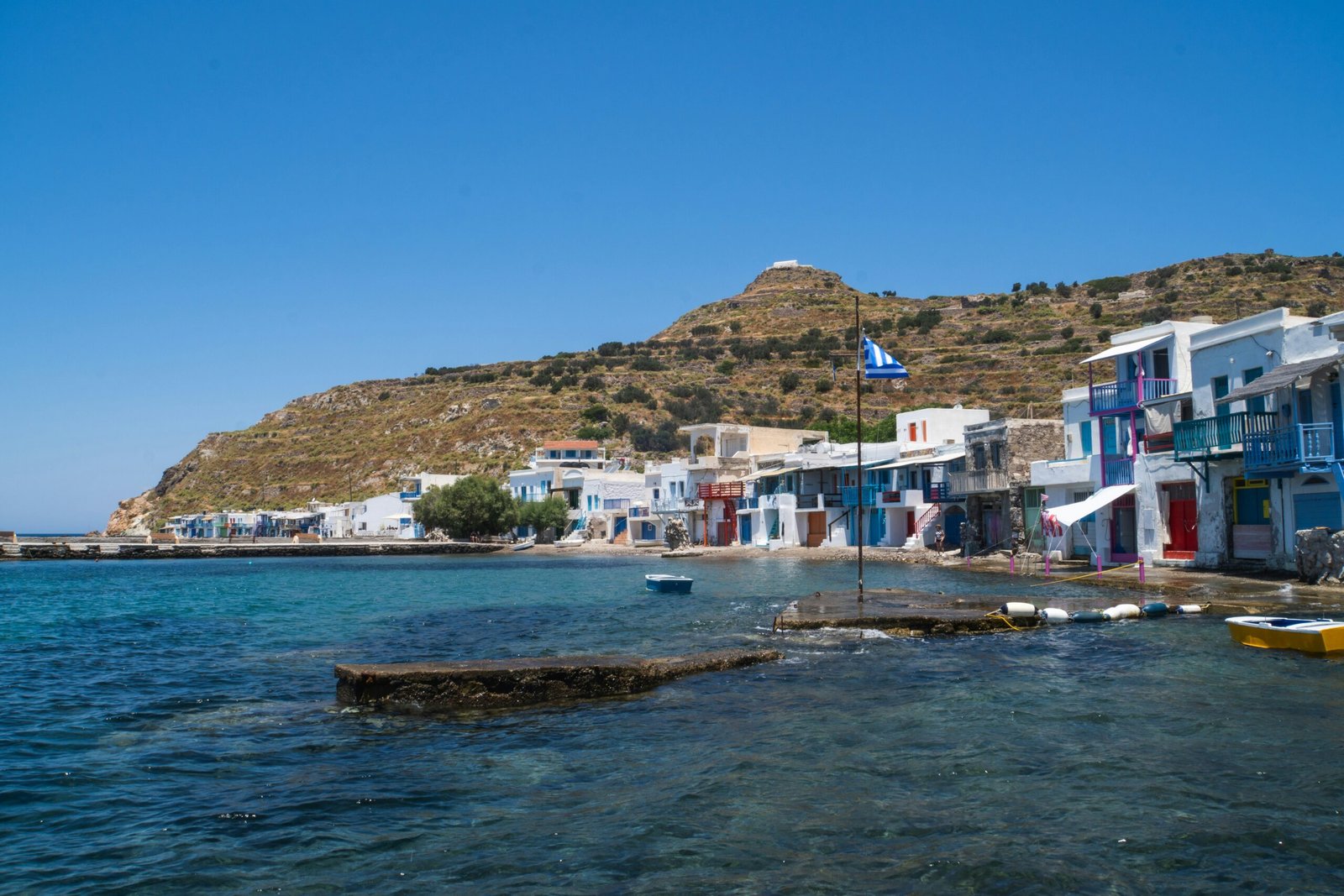 Colorful waterfront houses and clear summer water in Milos, Greece