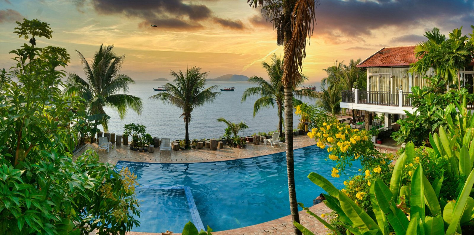 Sunset pool and palm trees in Kep, Cambodia, matching the calm and luxurious atmosphere of a tropical wellness retreat.