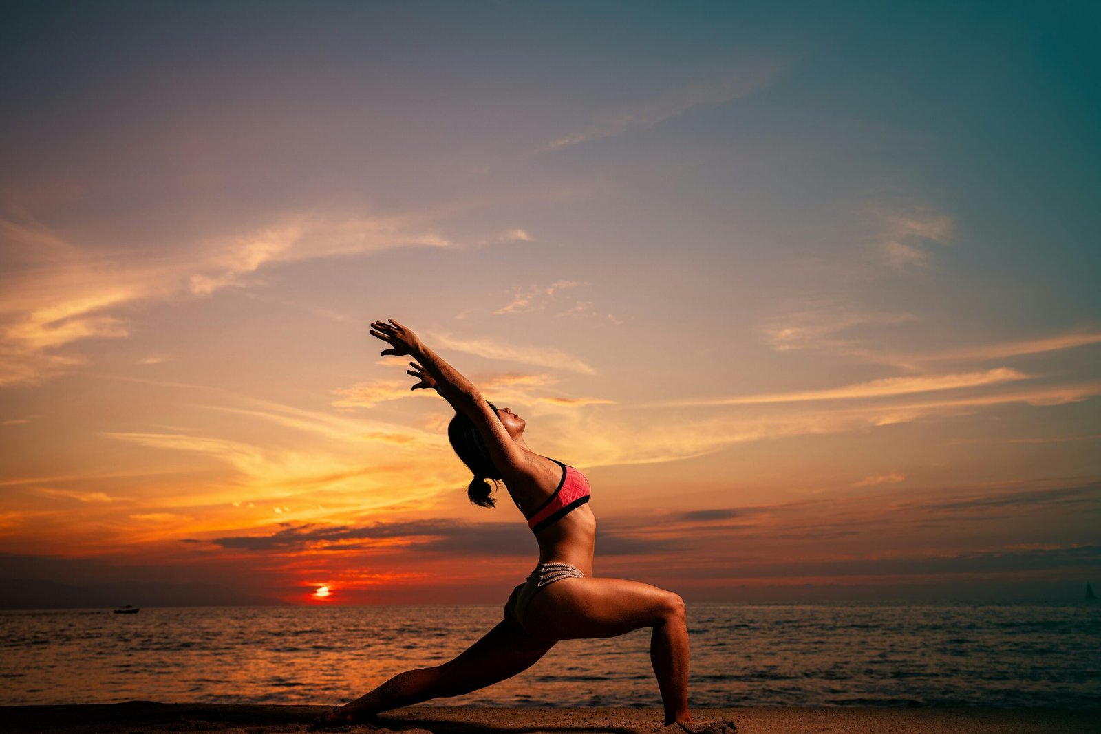 Best SEO Alt Tag: "A woman practicing a crescent lunge yoga pose on a sandy beach at sunset, embodying the vibrant Atlantic energy and balance found at a Portuguese seaside wellness retreat.