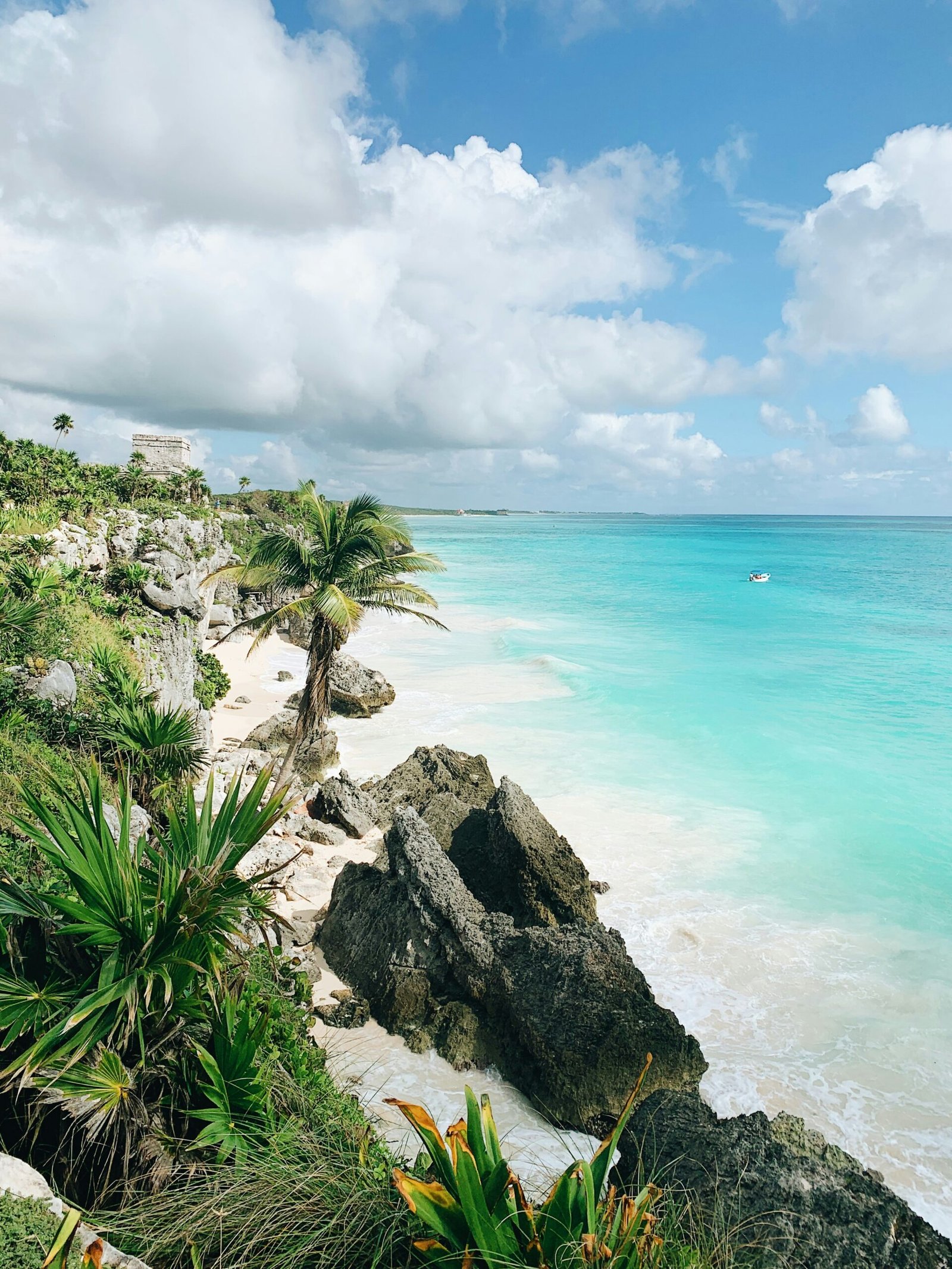 Palm-framed beach in Tulum with a rustic hut and calm morning light for a March yoga retreat in Mexico.