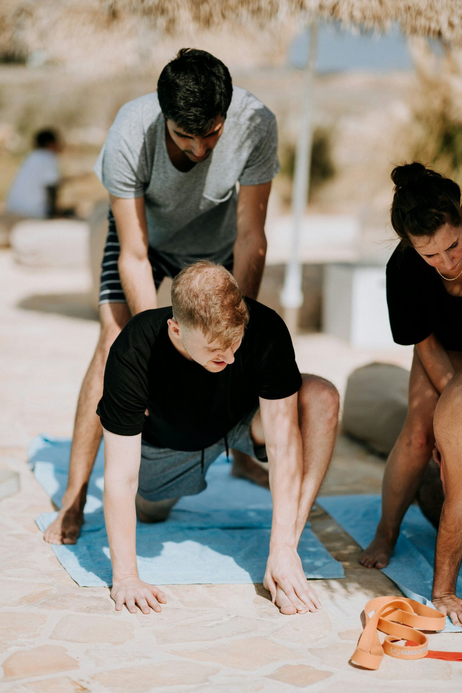 A professional yoga instructor providing a safe physical adjustment to a student, demonstrating the technical expertise and personalized attention found in a high-quality wellness retreat.