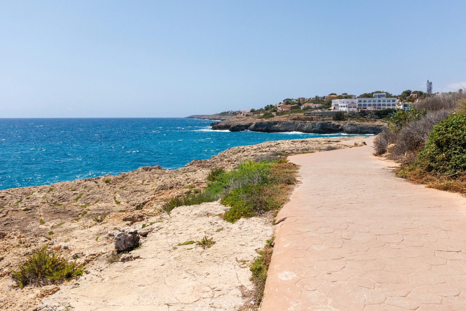 Coastal path in Mallorca, Spain, leading toward the sea beside cliffs and beach views.