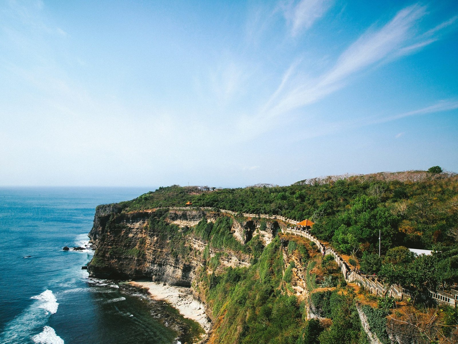 A traditional Balinese split gateway (Candi Bentar) at Uluwatu overlooking the Indian Ocean during a golden sunset, symbolizing the spiritual journey of an October 2026 yoga retreat.