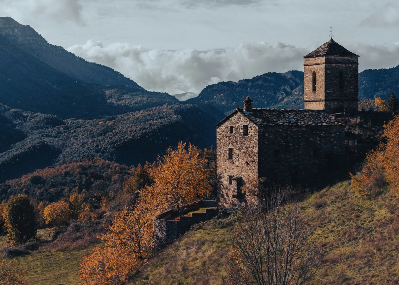 Historic monastery on a green hillside in Montserrat, Spain, surrounded by rugged mountains and lush vegetation.
