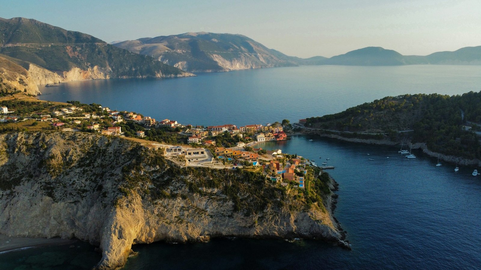 Coastal village in Assos, Kefalonia, creating a peaceful September retreat setting between cliffs and the sea.