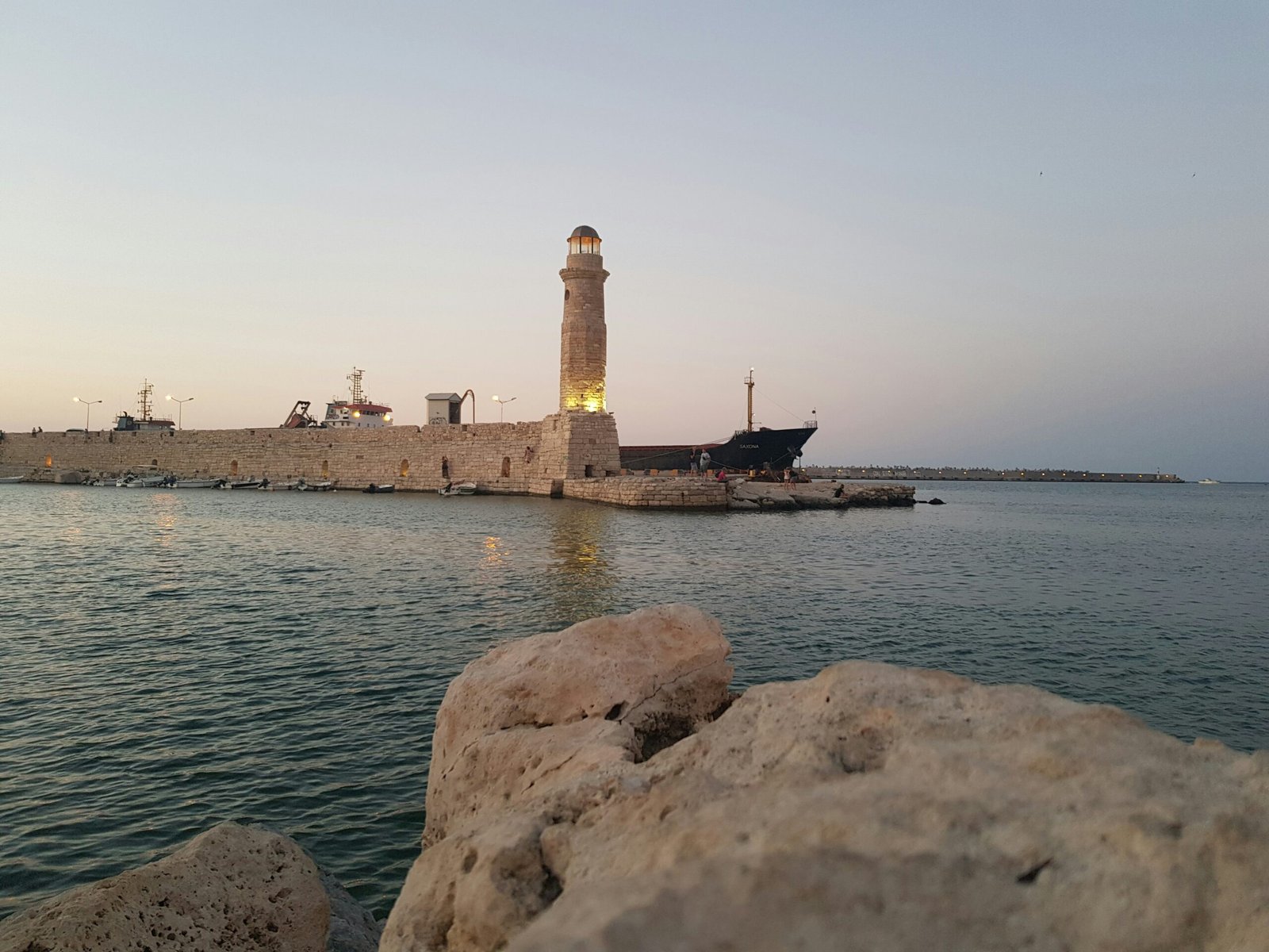 : Quiet lighthouse and harbor in Rethymno, Crete, creating a peaceful winter retreat scene by the sea.