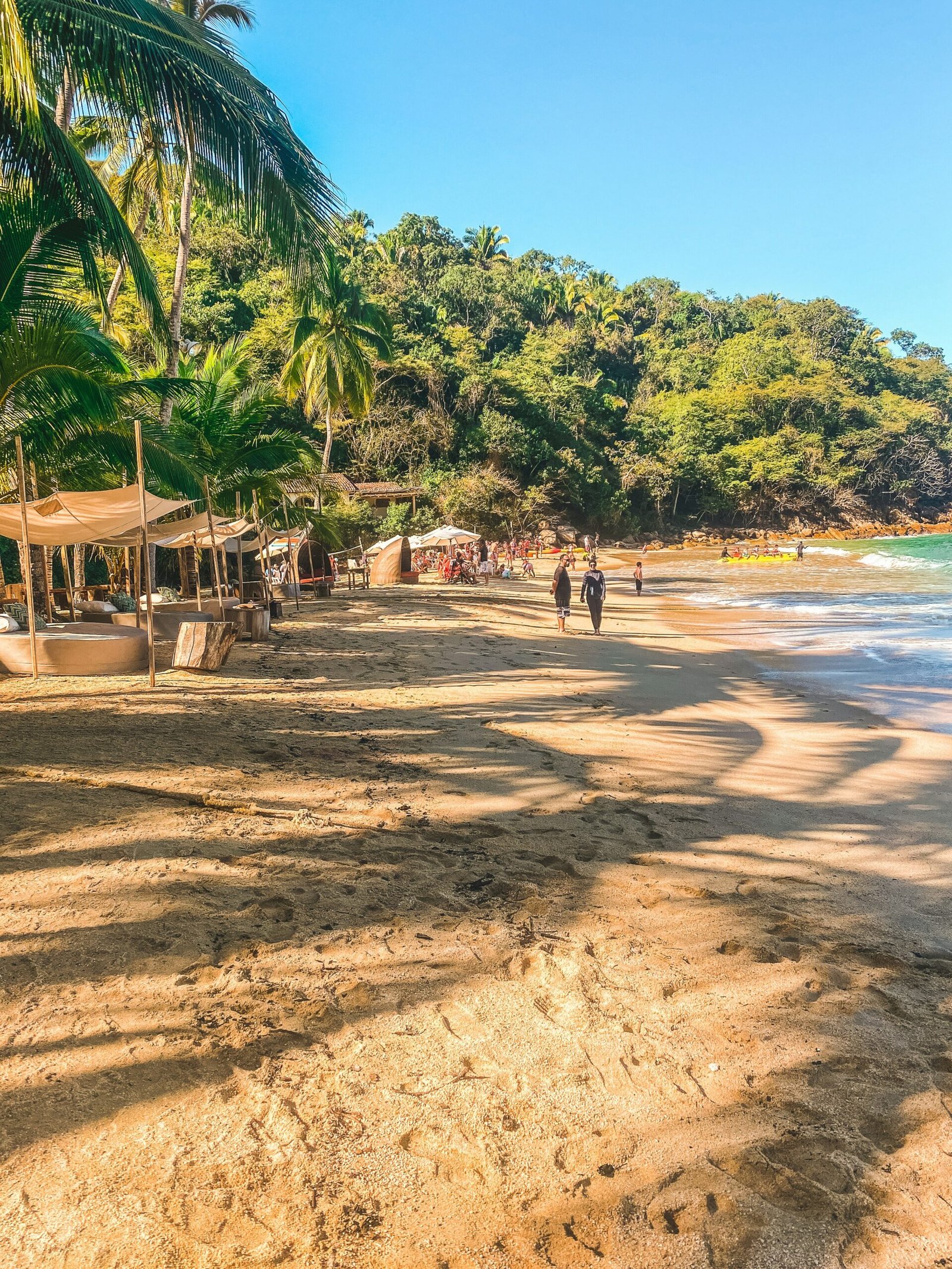 Palm-lined beach in Puerto Vallarta, Jalisco, with people walking along the shore