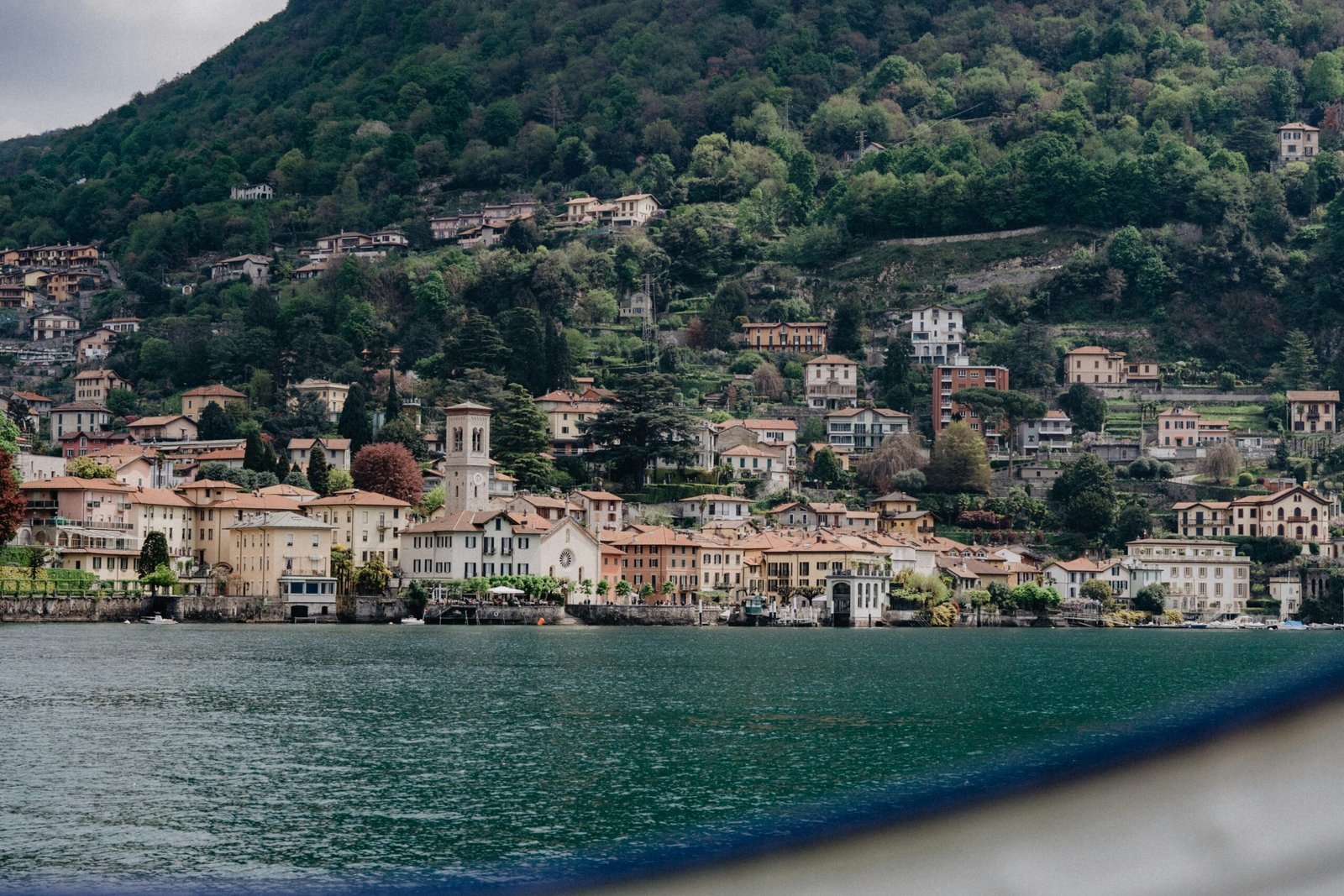 Lakeside view of Como in spring with hillside buildings, blossoms, and a peaceful waterside setting.