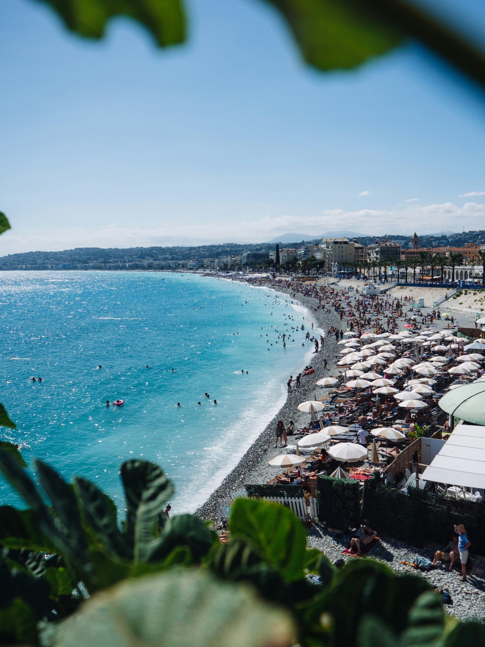 Sunny beach in Nice with bright Mediterranean water, ideal for a vibrant summer yoga retreat in France.
