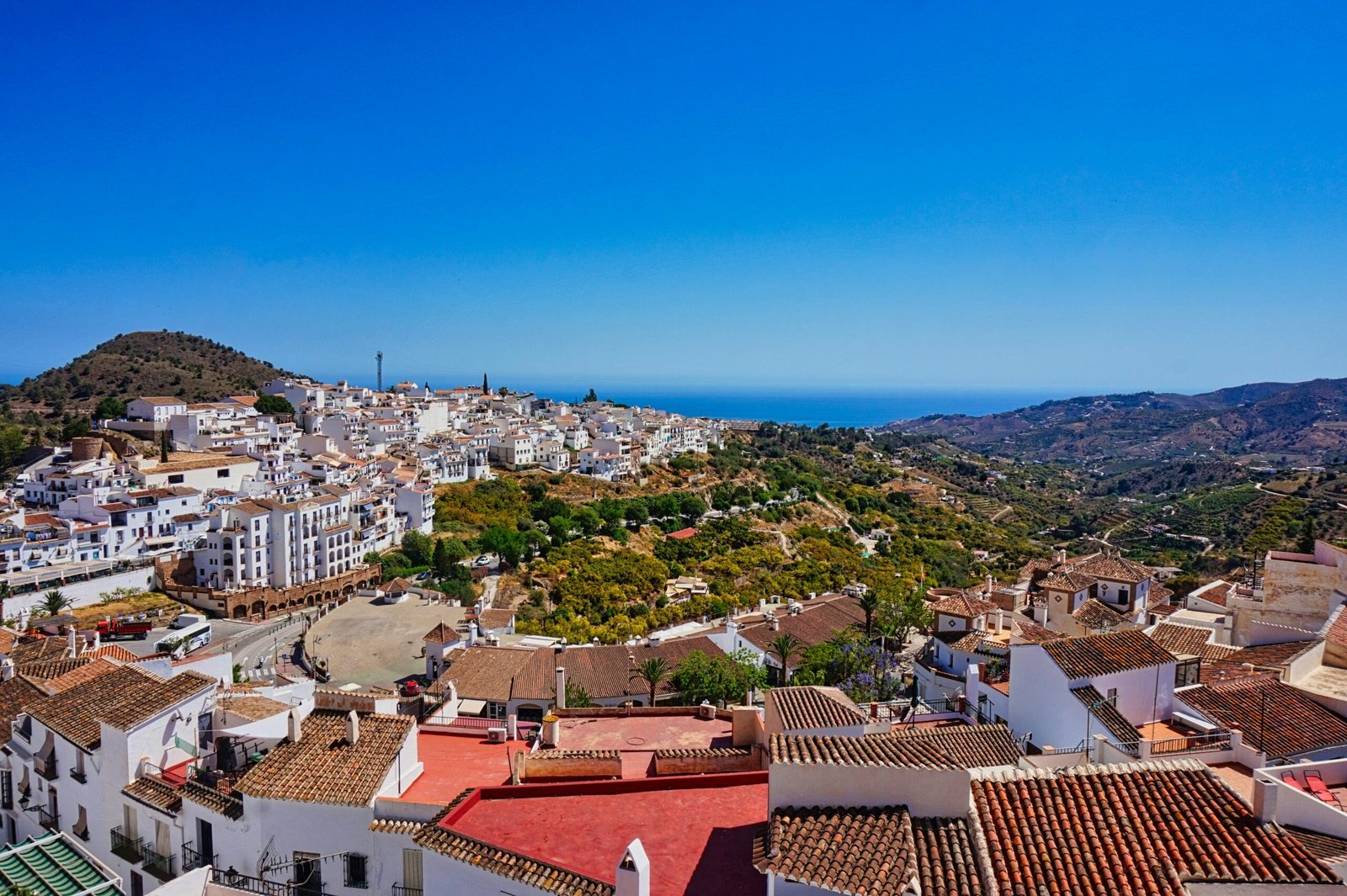 View of Frigiliana in Andalusia, Spain, with whitewashed houses, mountains, and blue winter sky.
