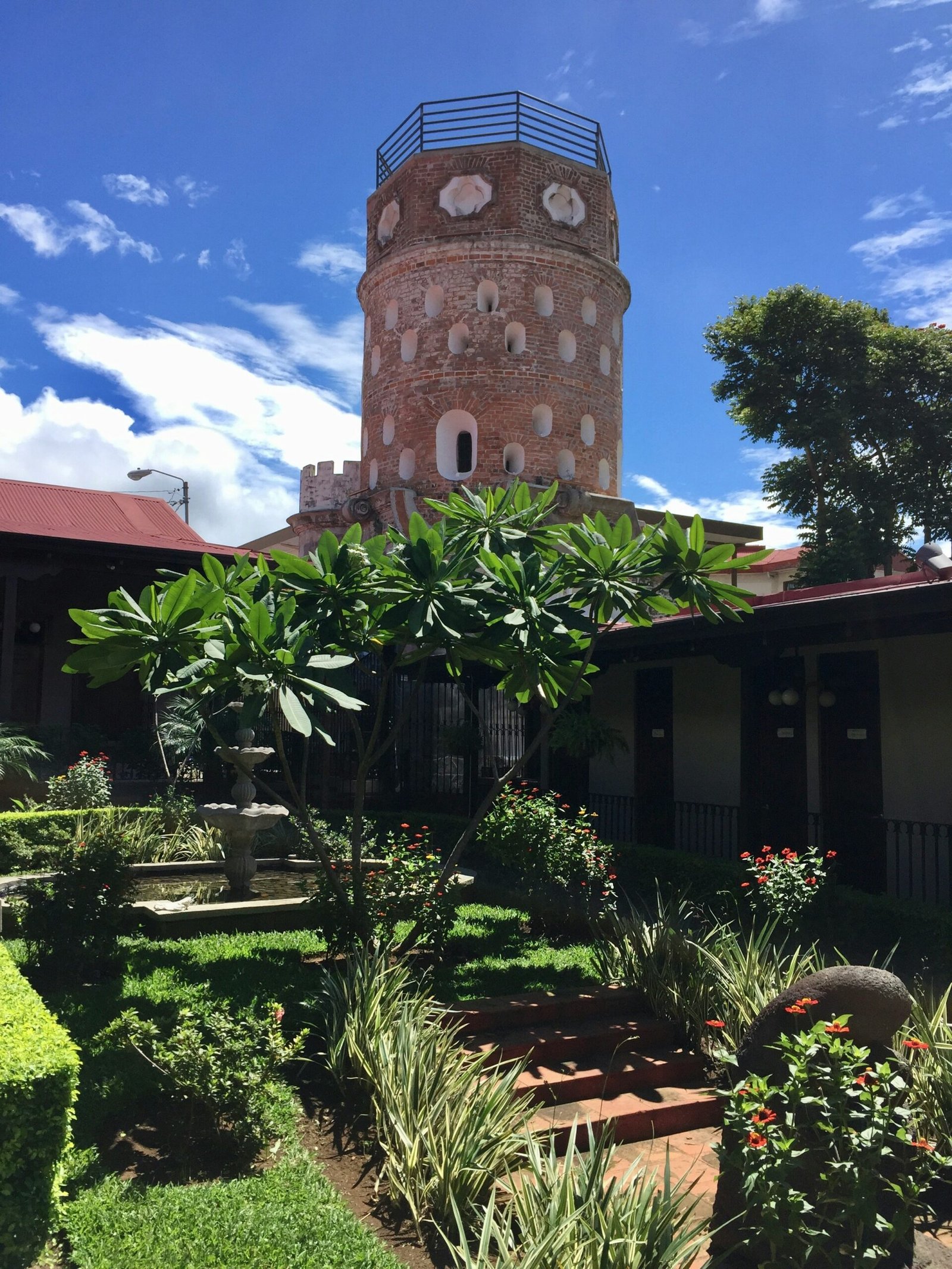 Historic facade framed by trees in central Heredia, Costa Rica.