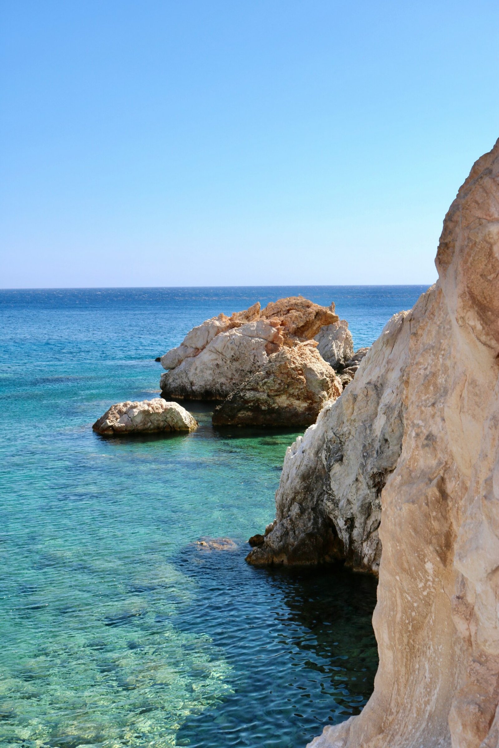 Rocky coastline in Polyaigos with vivid blue water, fitting a nature-led June retreat in the Greek islands.
