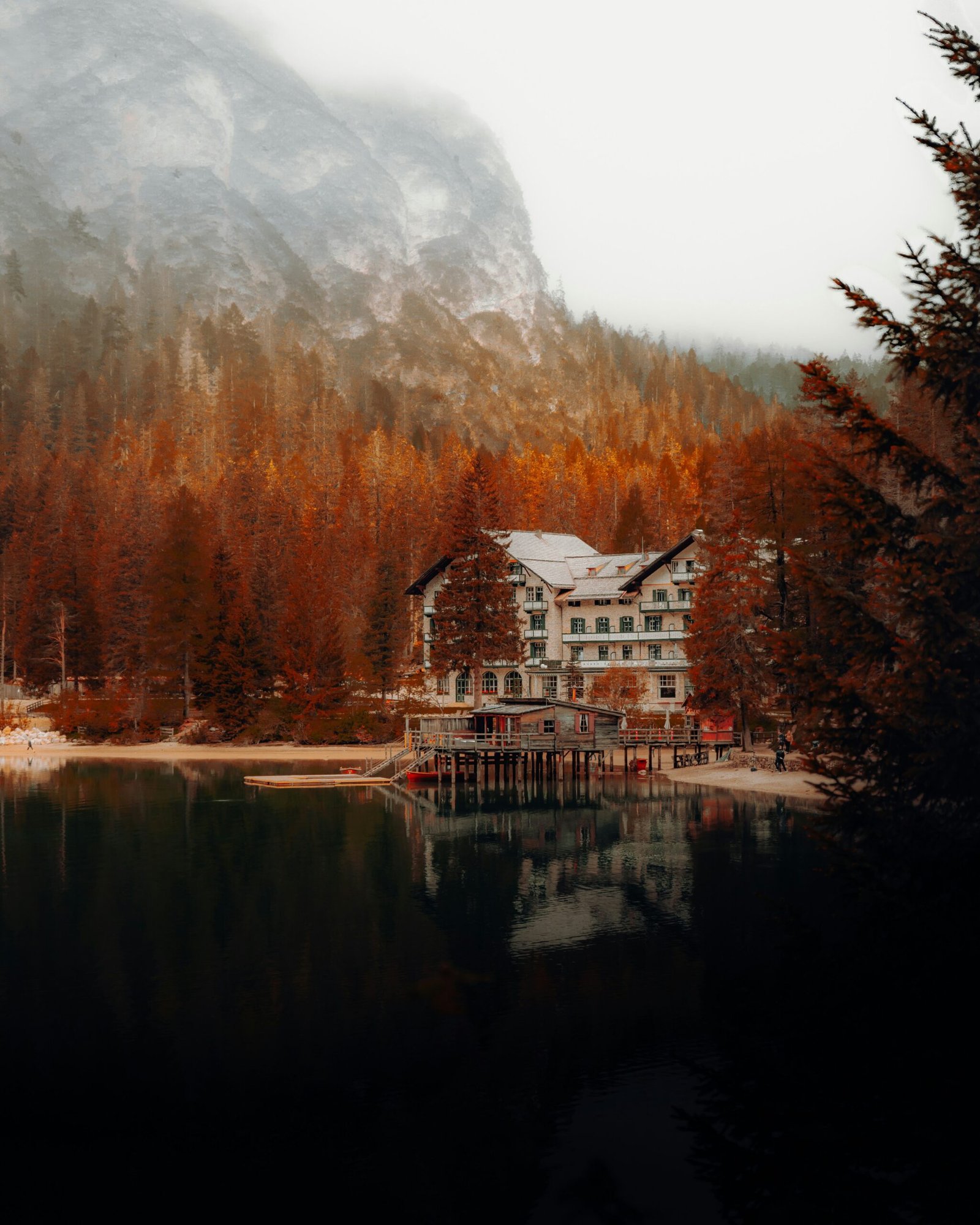 Autumn-toned boathouse at Lago di Braies with still water and mountain reflections, fitting the composed and reflective feel of September.