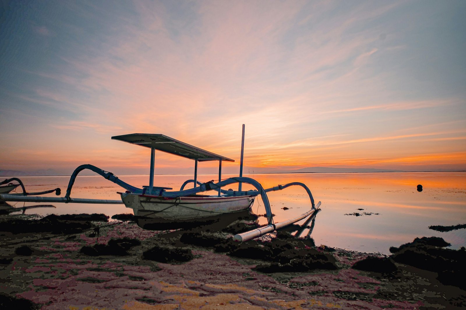 still sanur shoreline with fishing boat and soft dawn light in bali