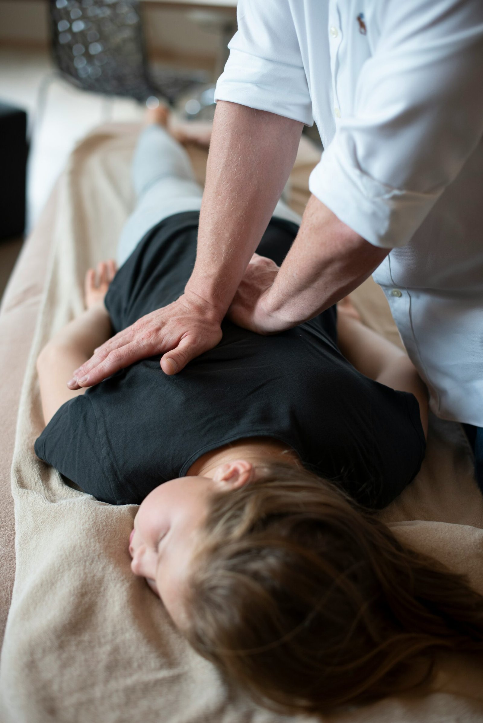 Woman receiving a back massage from a man during a hands-on bodywork or spa treatment session.