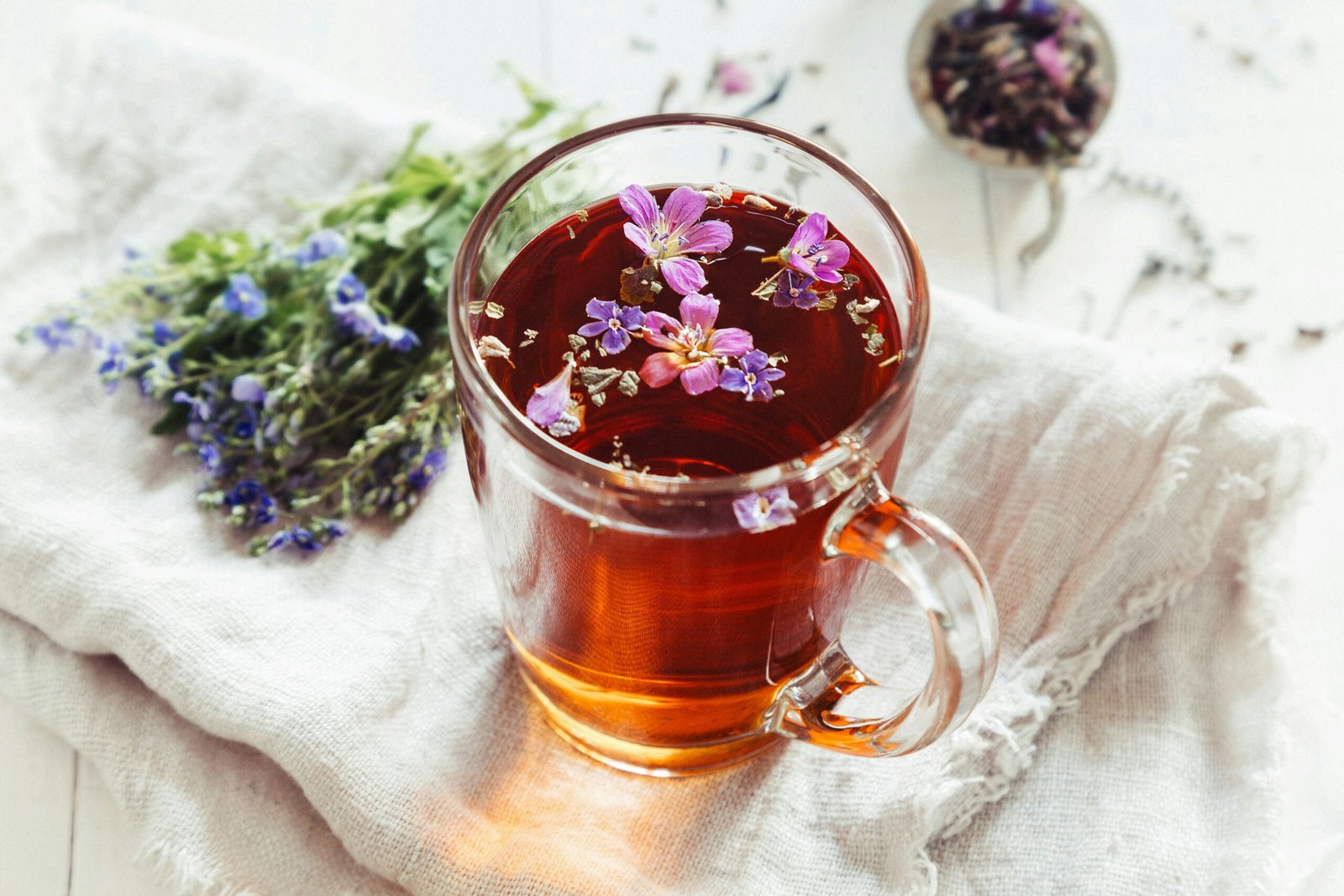 Herbal tea with blossoms arranged beside it for a calm and abundant spring retreat moment.