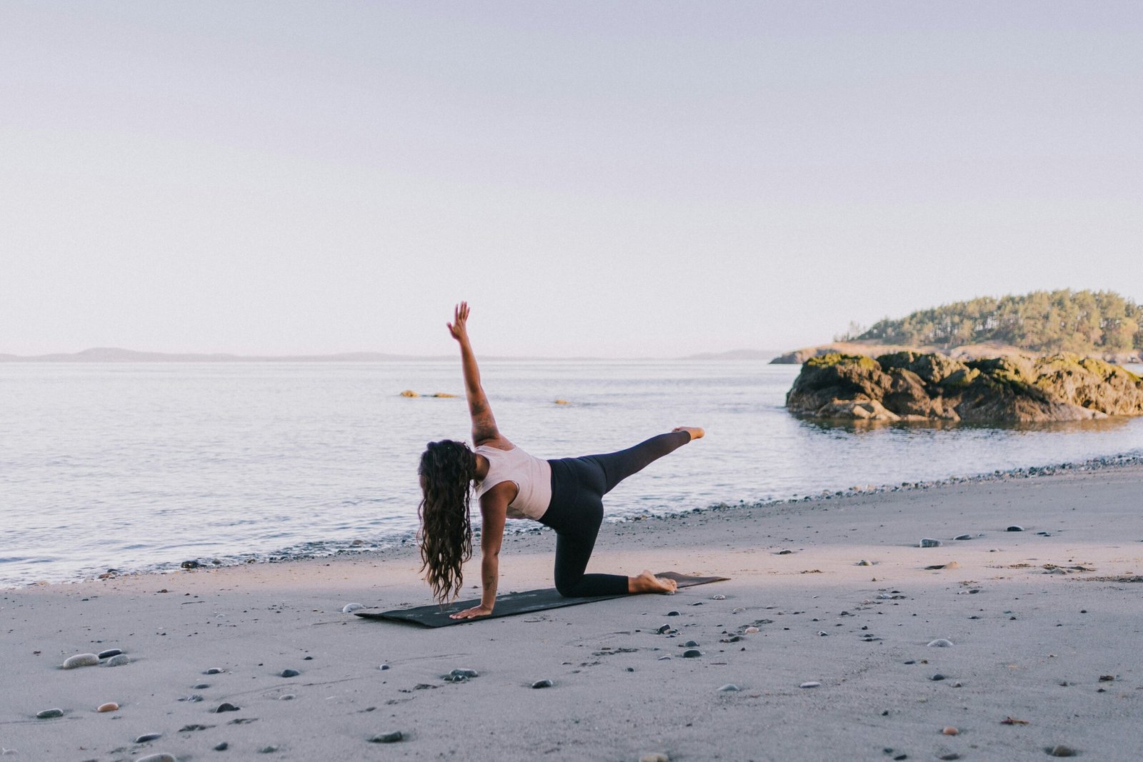 girl doing yoga in march on a deserted beach close to the location of her retreat