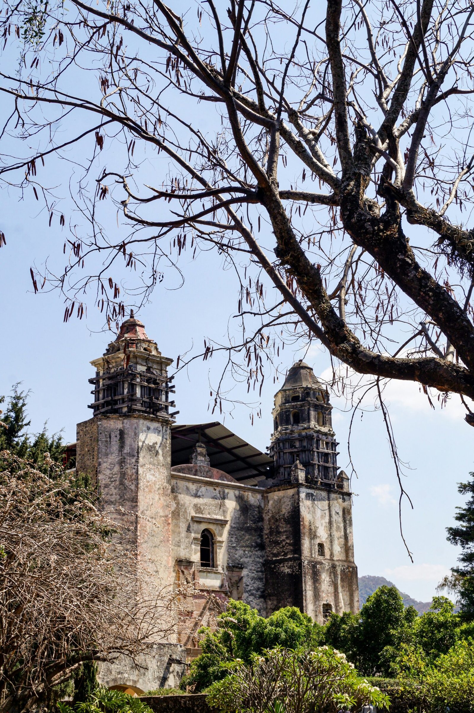 Historic church building in Tepoztlán, Morelos, Mexico, with trees and blue sky.