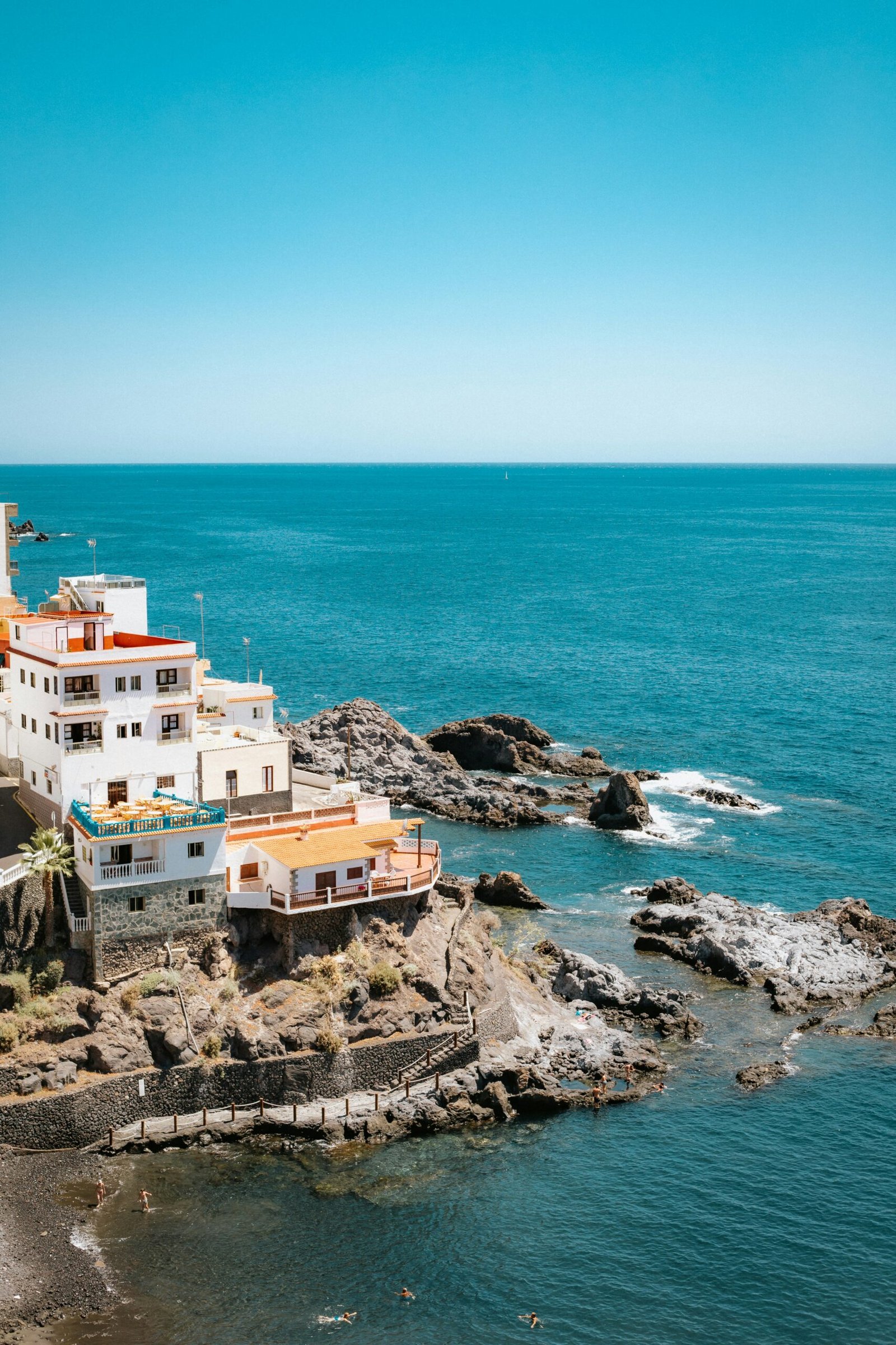 Building perched on a rocky cliff above the ocean along a rugged coastline