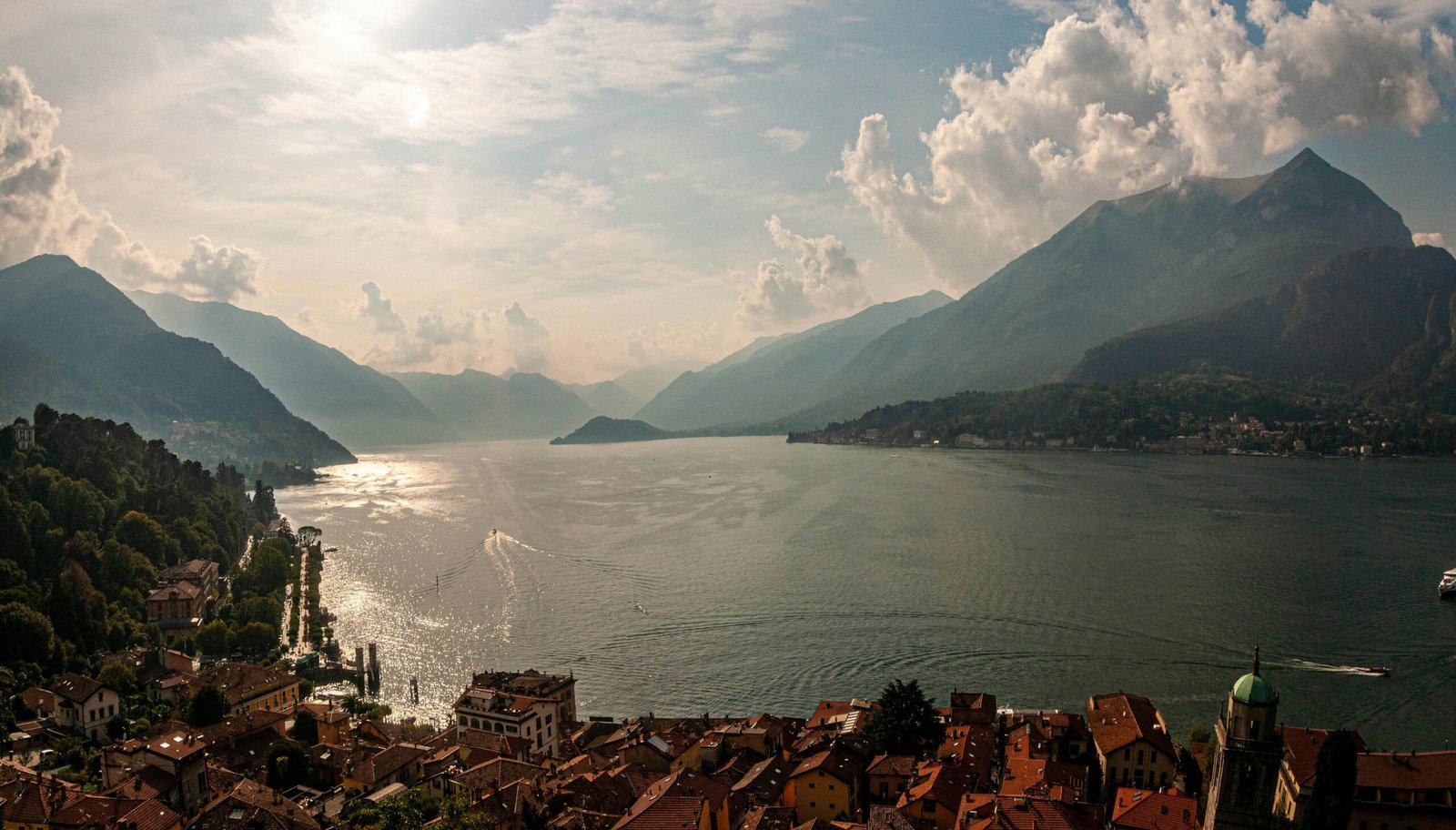 Panoramic view across Lake Como from Bellagio with hillside buildings and tranquil water.