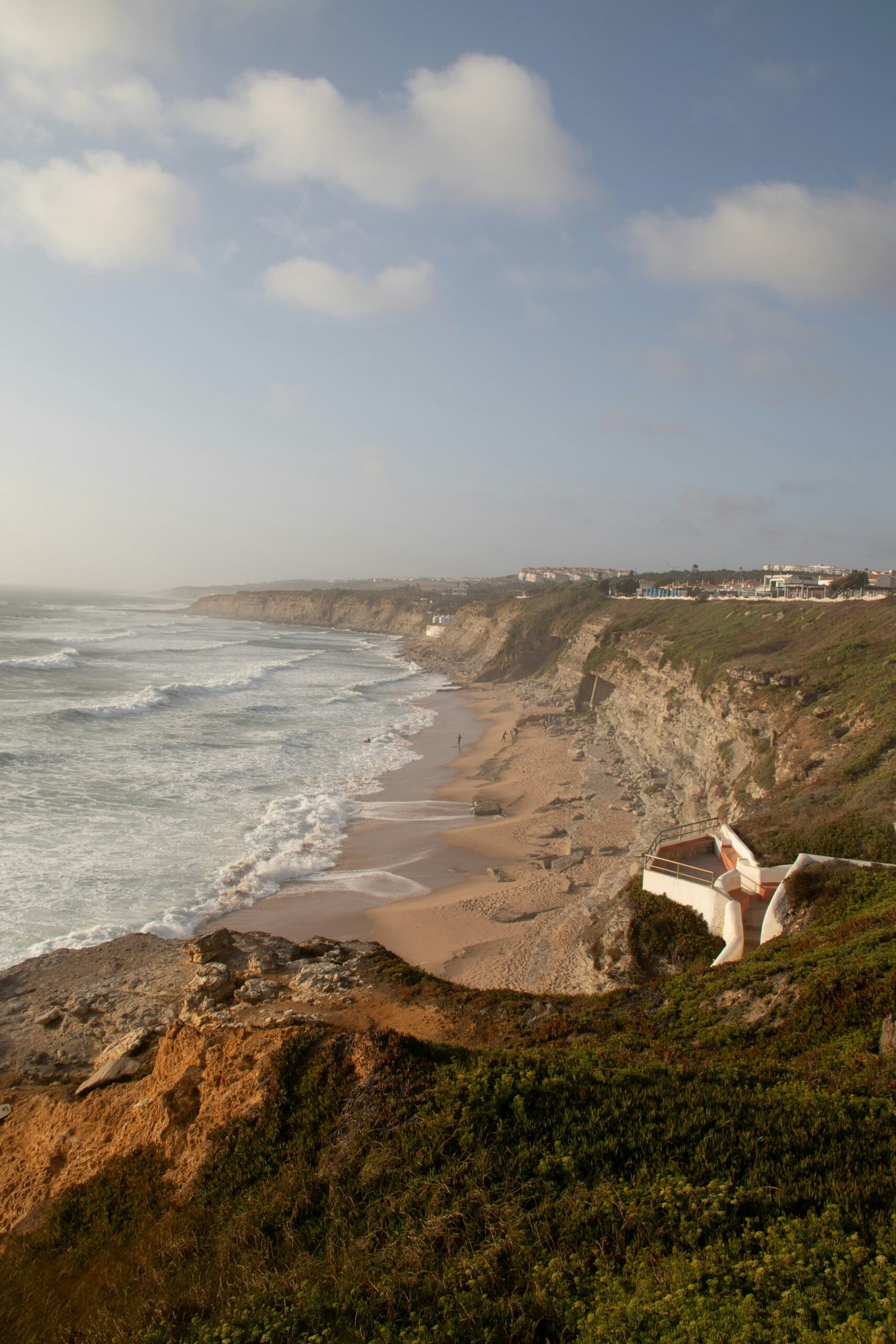 A wide-angle view of the rugged Atlantic coastline and sandy beaches near Ericeira, Portugal, illustrating the 'Ocean Air' environment for coastal yoga and wellness retreats near Lisbon.