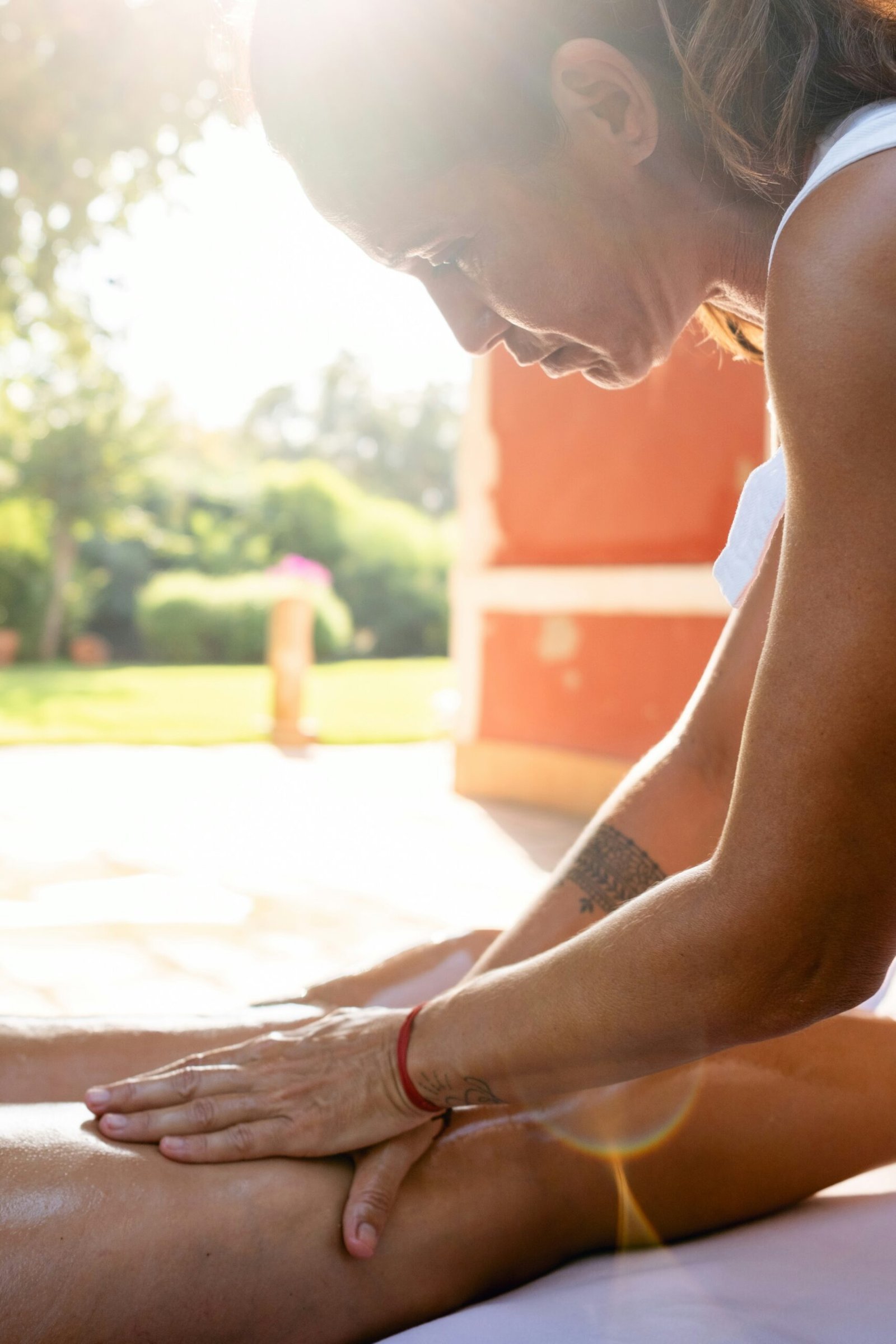Woman in a white tank top stretching her legs during an outdoor fitness session.