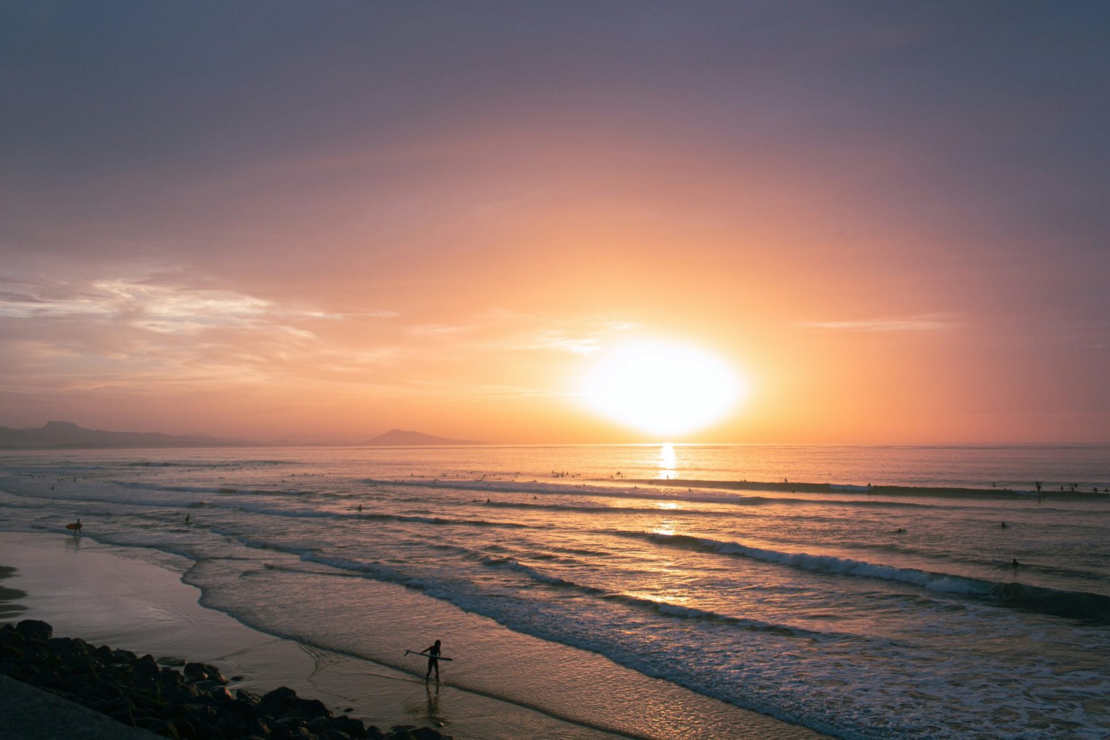 Sunset surfers in Biarritz creating an energizing Atlantic backdrop for a summer yoga retreat in France.