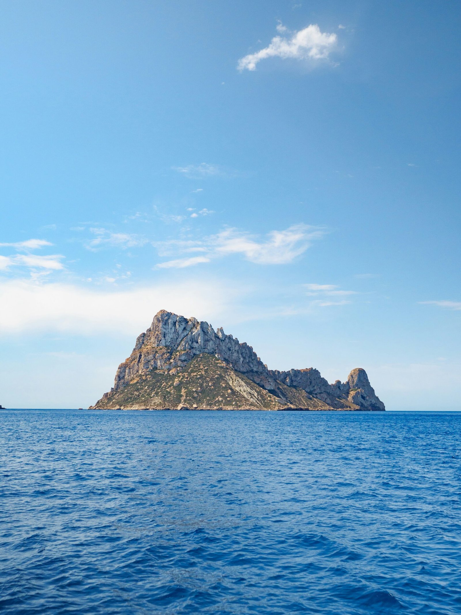 Es Vedra off the coast of Ibiza under bright summer light and open blue sea.