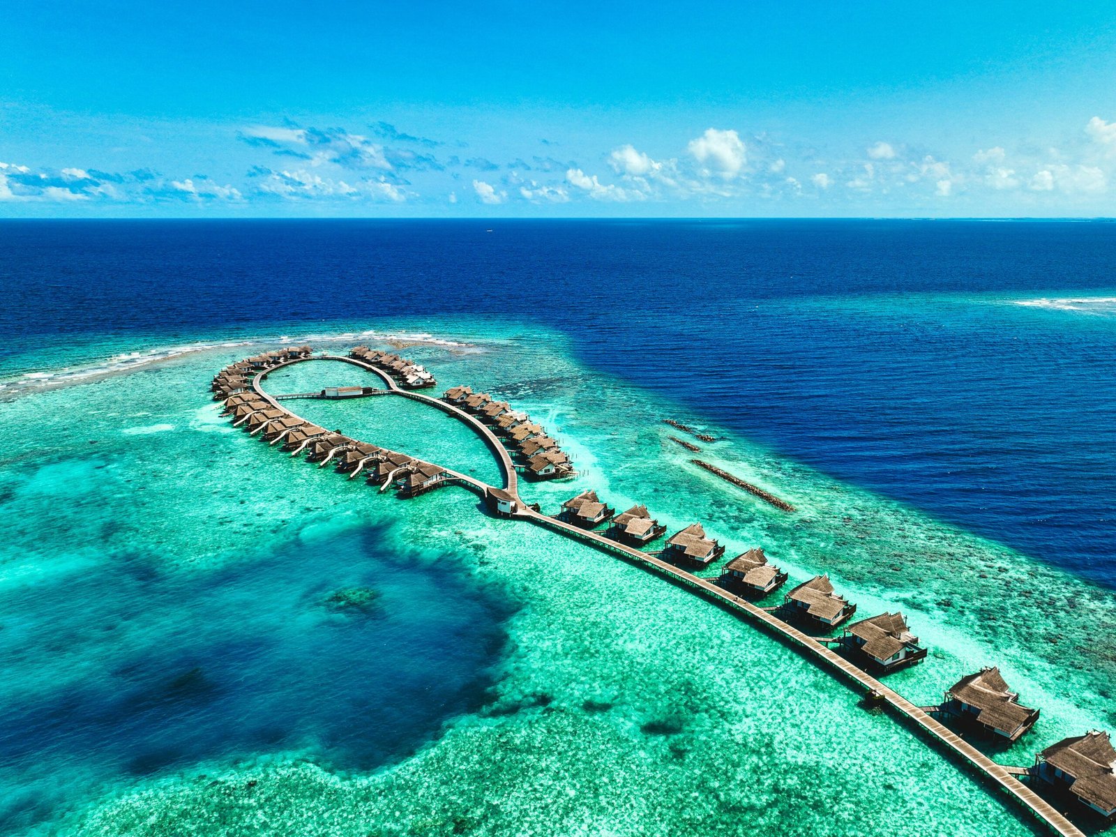 Overwater villas at a Maldives island resort surrounded by a bright blue lagoon.