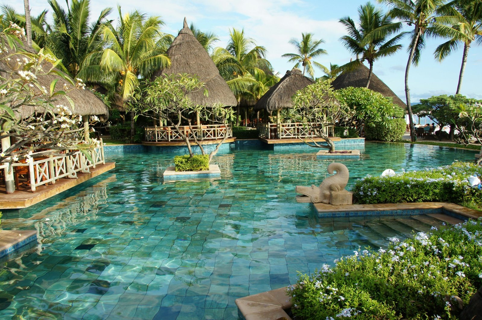 Tranquil resort pool with a statue at the center of a restorative retreat space