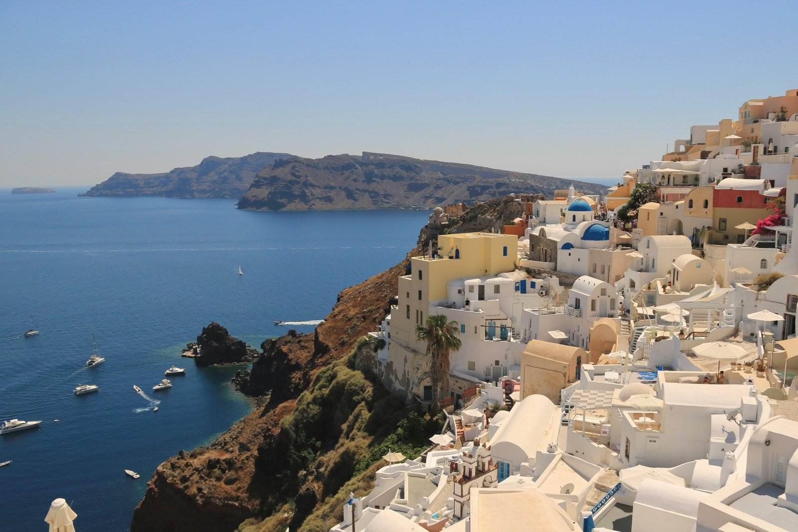 Cliffside view over Fira in Santorini with white buildings above the Aegean Sea.