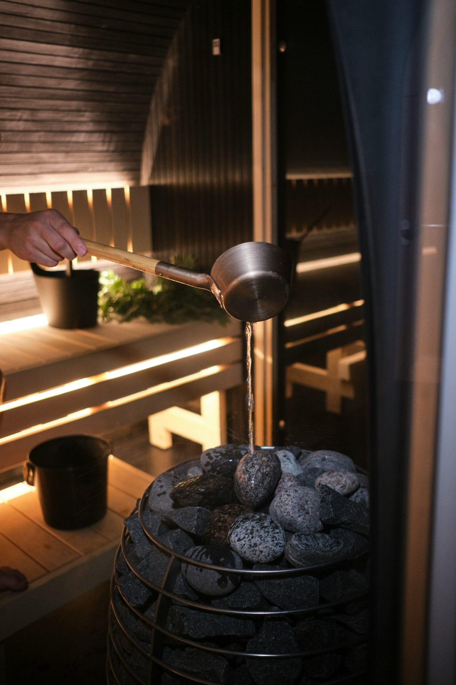 Sauna steam room with a person preparing food beside an electric stove in a warm wellness setting.