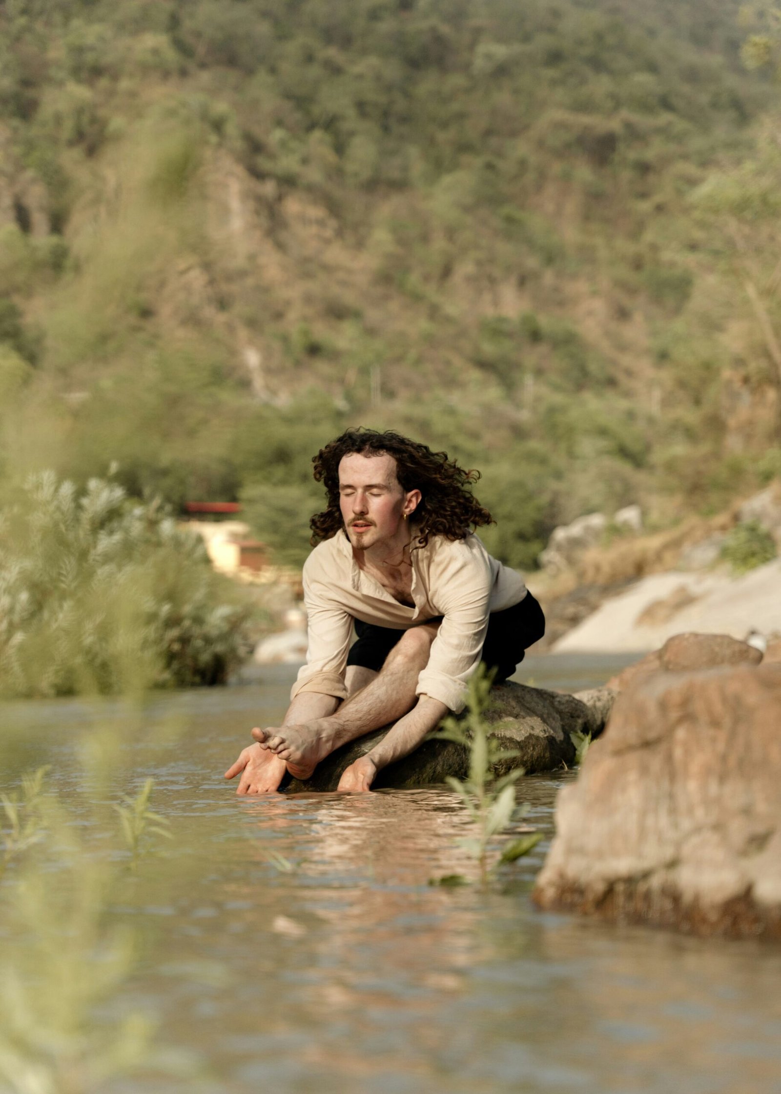 Man seated by the Ganga in Rishikesh, reflecting the inward focus and meditative depth of a July retreat in India.