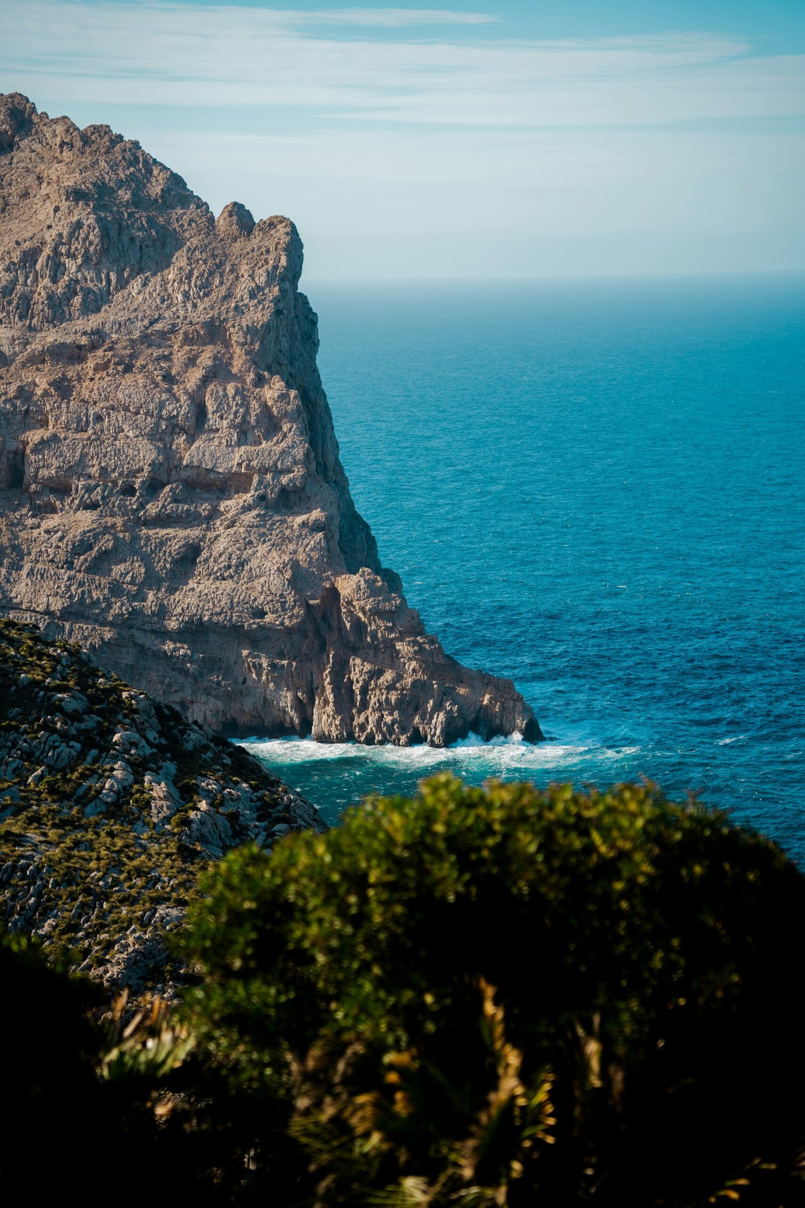 Rocky coastline in Mallorca, Spain, overlooking bright blue Mediterranean water.