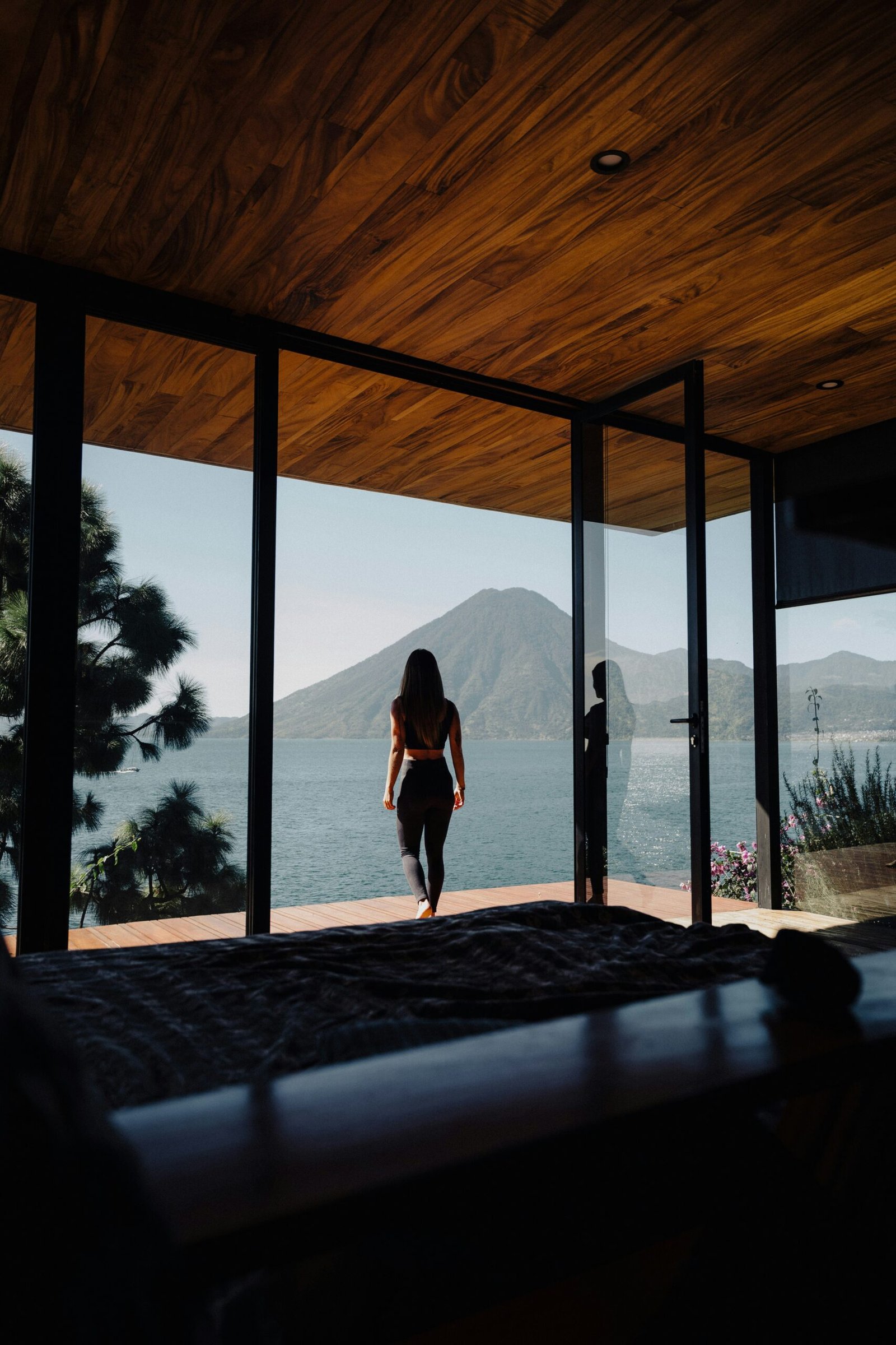 Person walking alone along a beach with mountains in the background, creating a calm tropical retreat scene.
