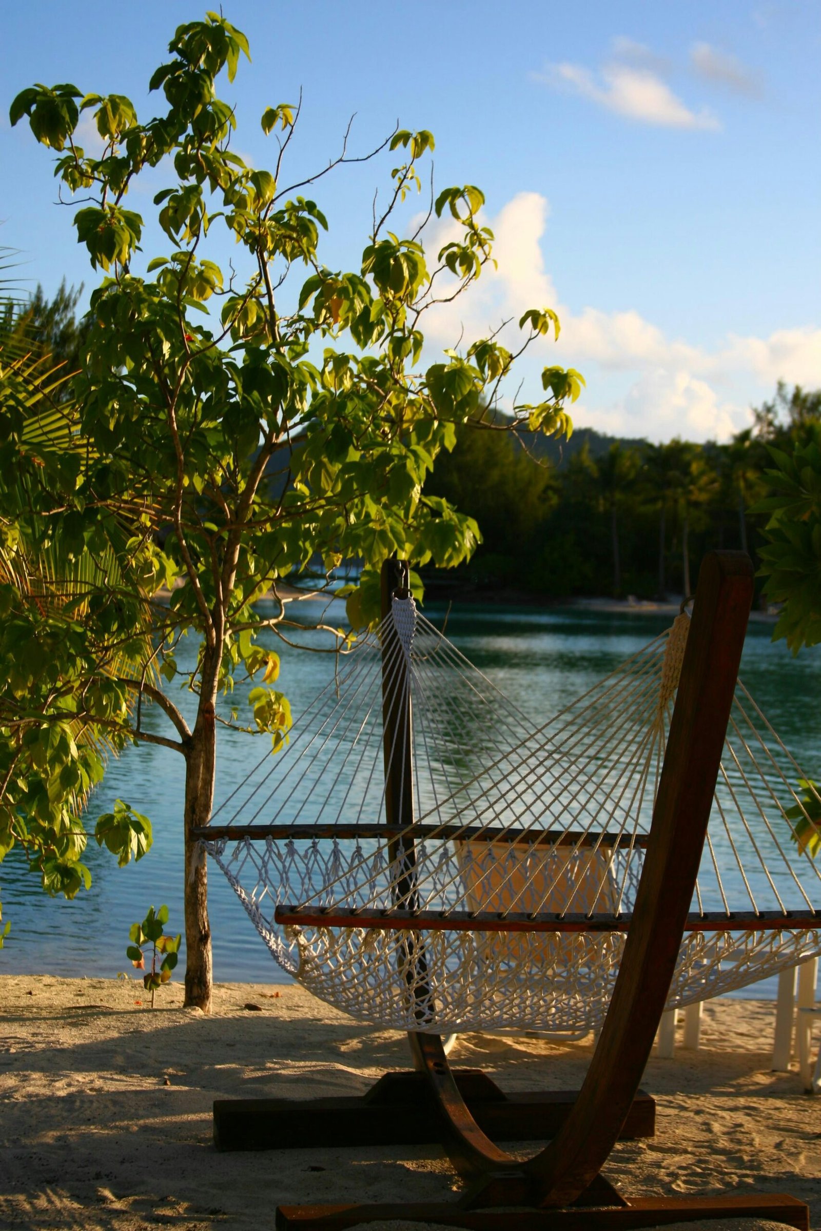 Hammock on a tropical beach with calm blue water for a laid-back July retreat escape.