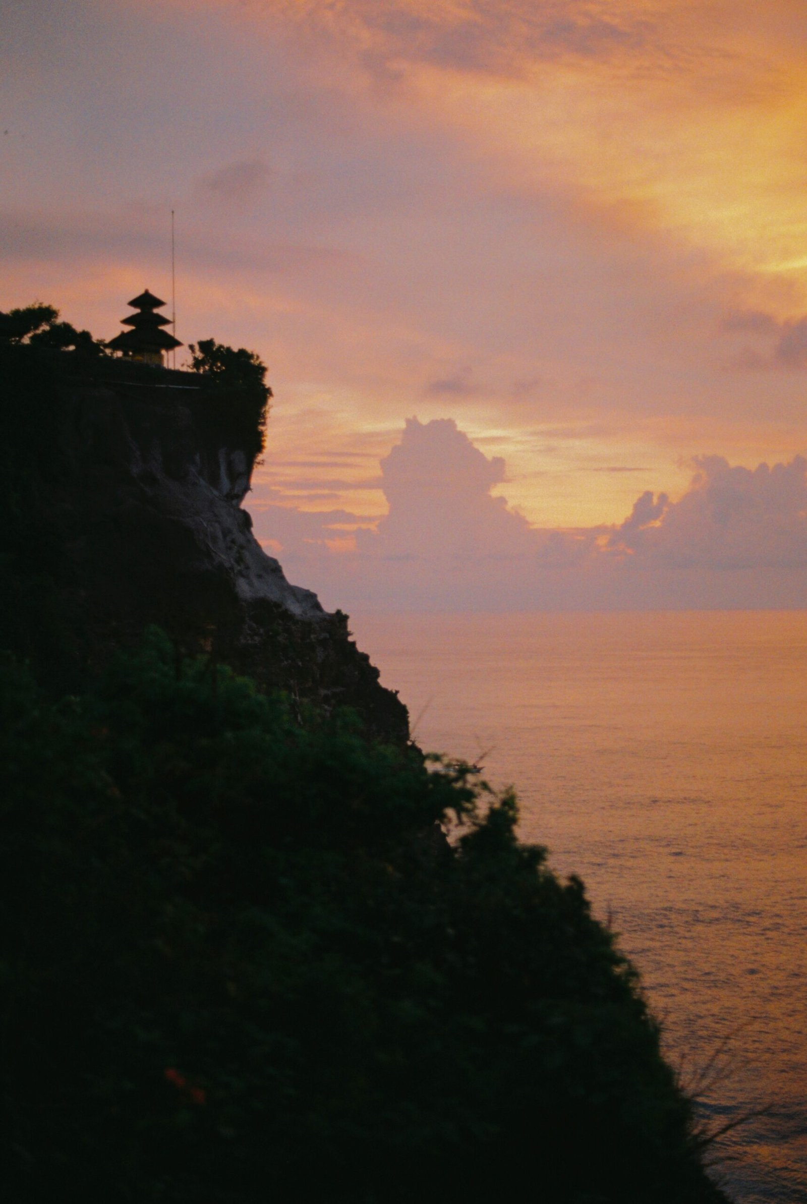 uluwatu temple at sunset with warm sky and ocean cliffs in bali