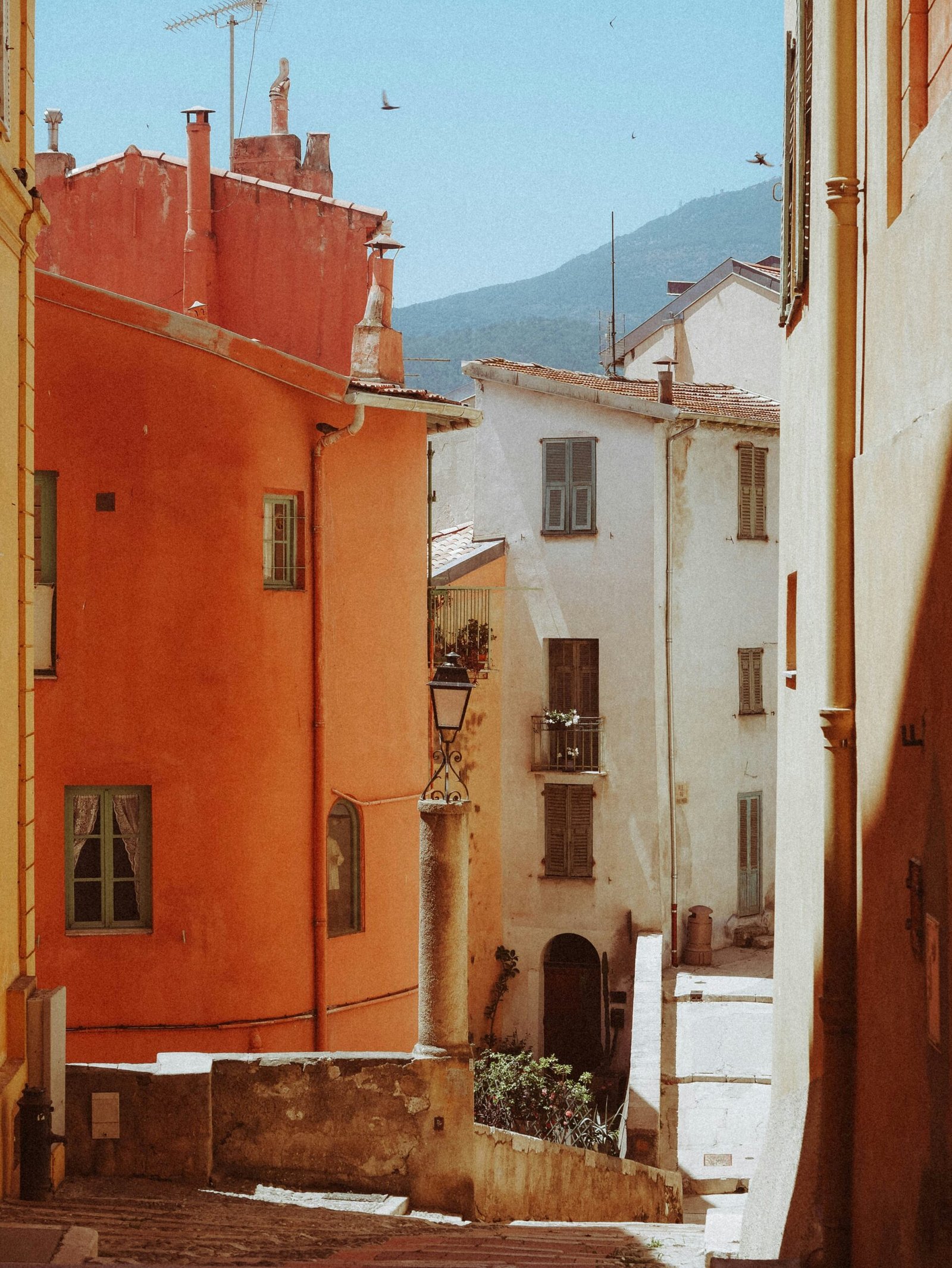 Warm street scene in Menton with colorful buildings and tower views, adding a relaxed South of France mood to a June yoga retreat.
