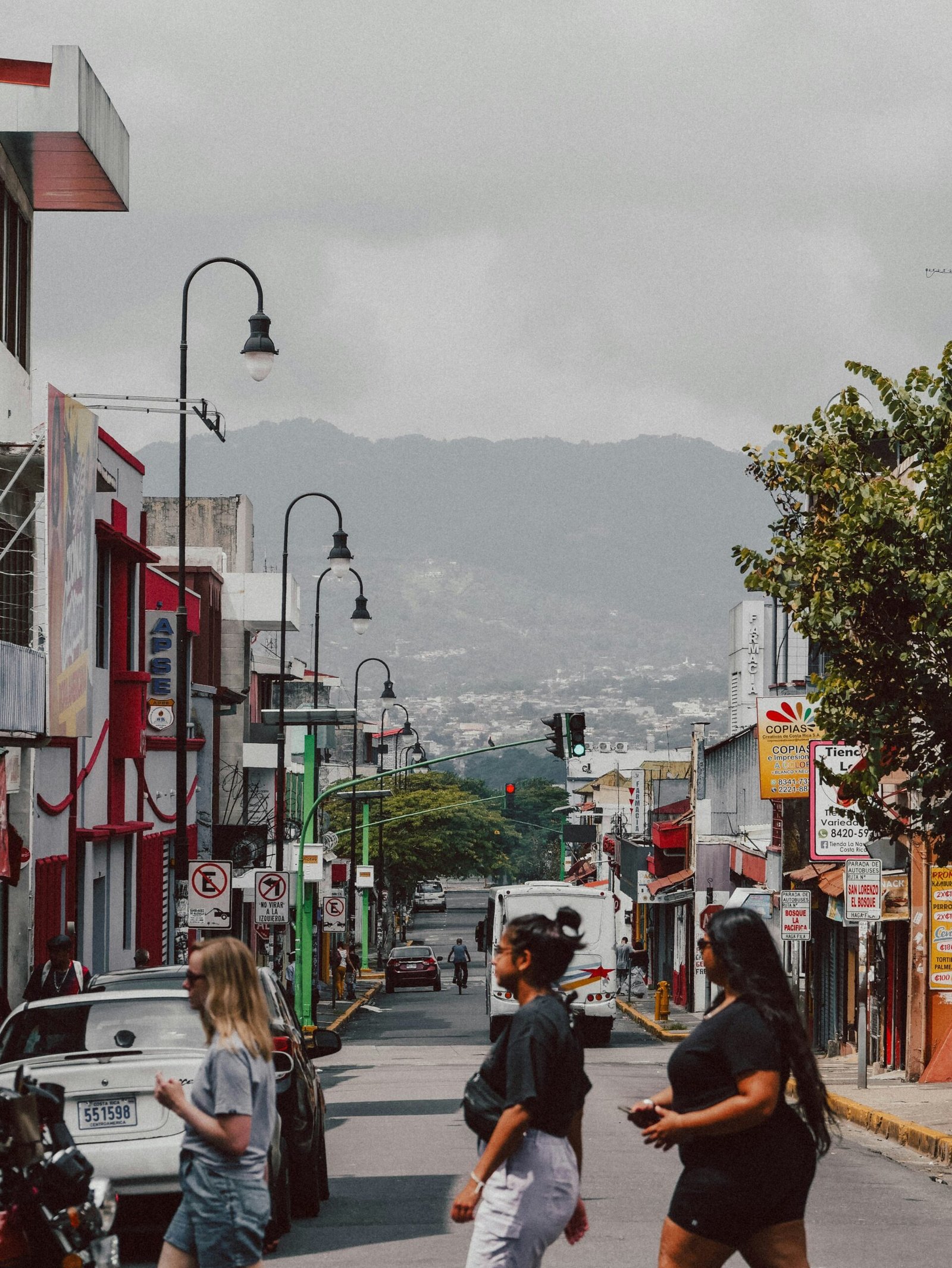 : Busy San José, Costa Rica street with cars, storefronts, and cloudy skies