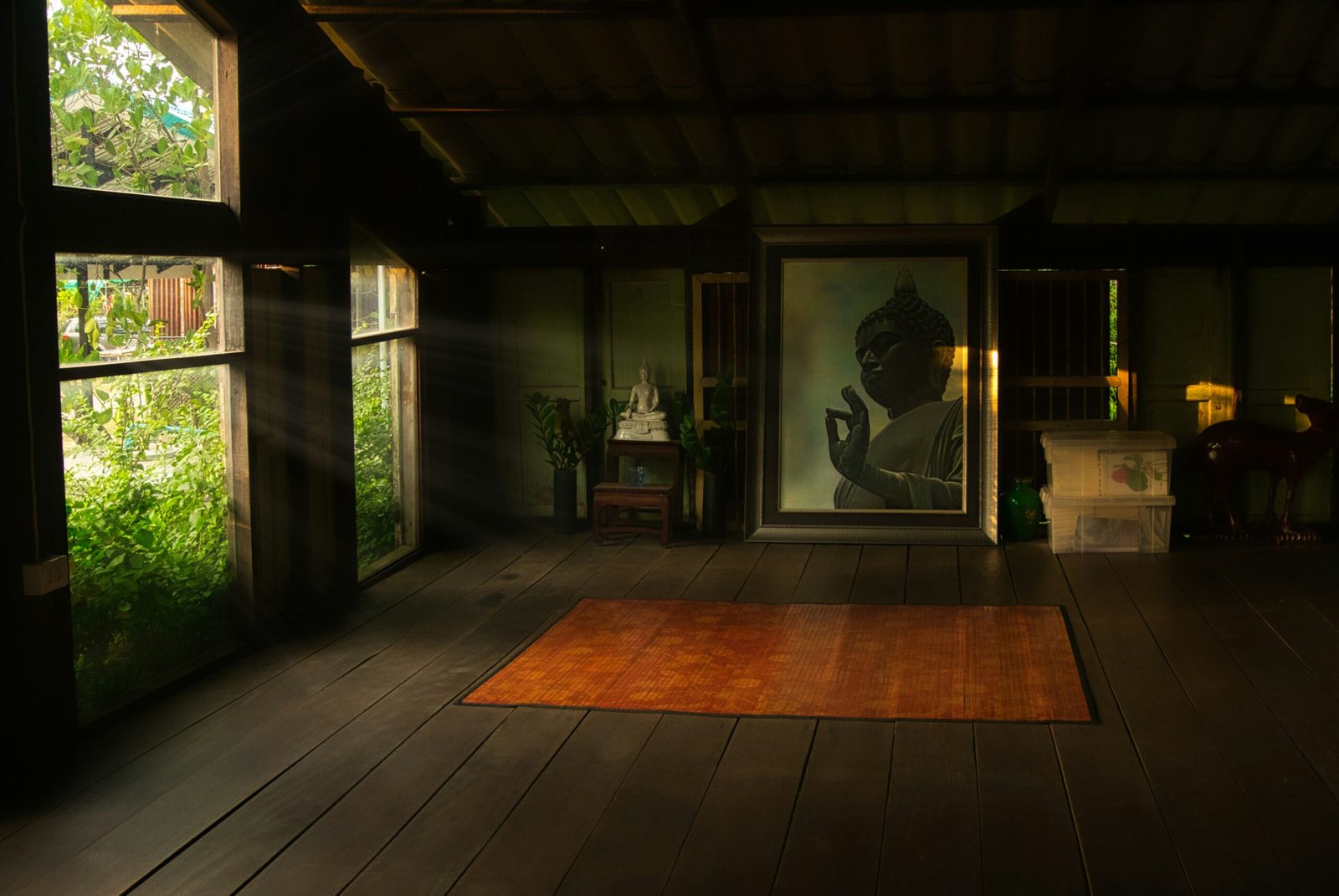 A serene wooden meditation room in Thailand with sunlight streaming onto an orange yoga mat and Buddha portrait, perfect for a 2026 introspective rainy season retreat.