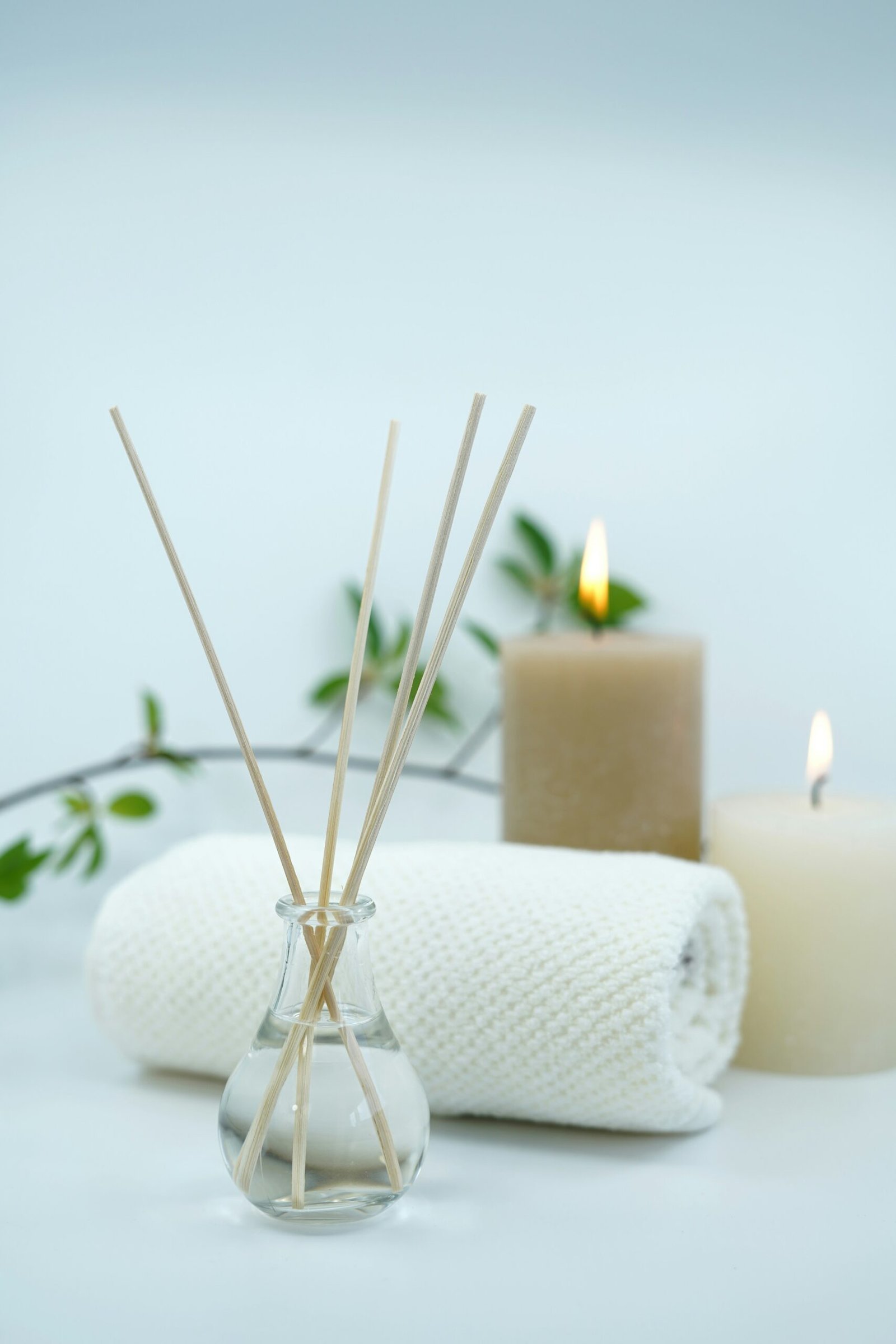 White pillar candle on a silver holder with spa-inspired styling, evoking a relaxing aromatherapy setting.